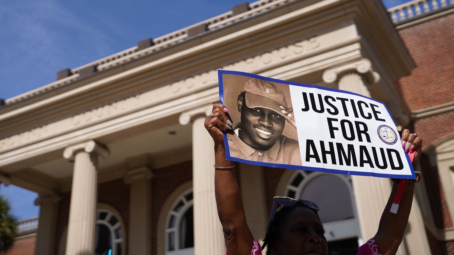 A demonstrator holds a sign at the Glynn County Courthouse as jury selection begins in the trial of the shooting death of Ahmaud Arbery on October 18, 2021 in Brunswick, Georgia. 