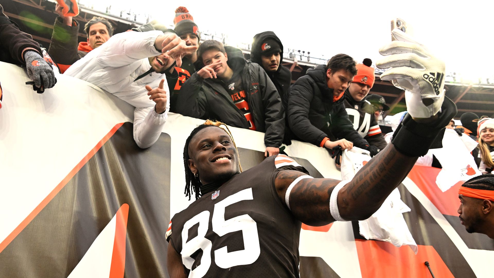 A Cleveland Browns football player takes a selfie with fans. 