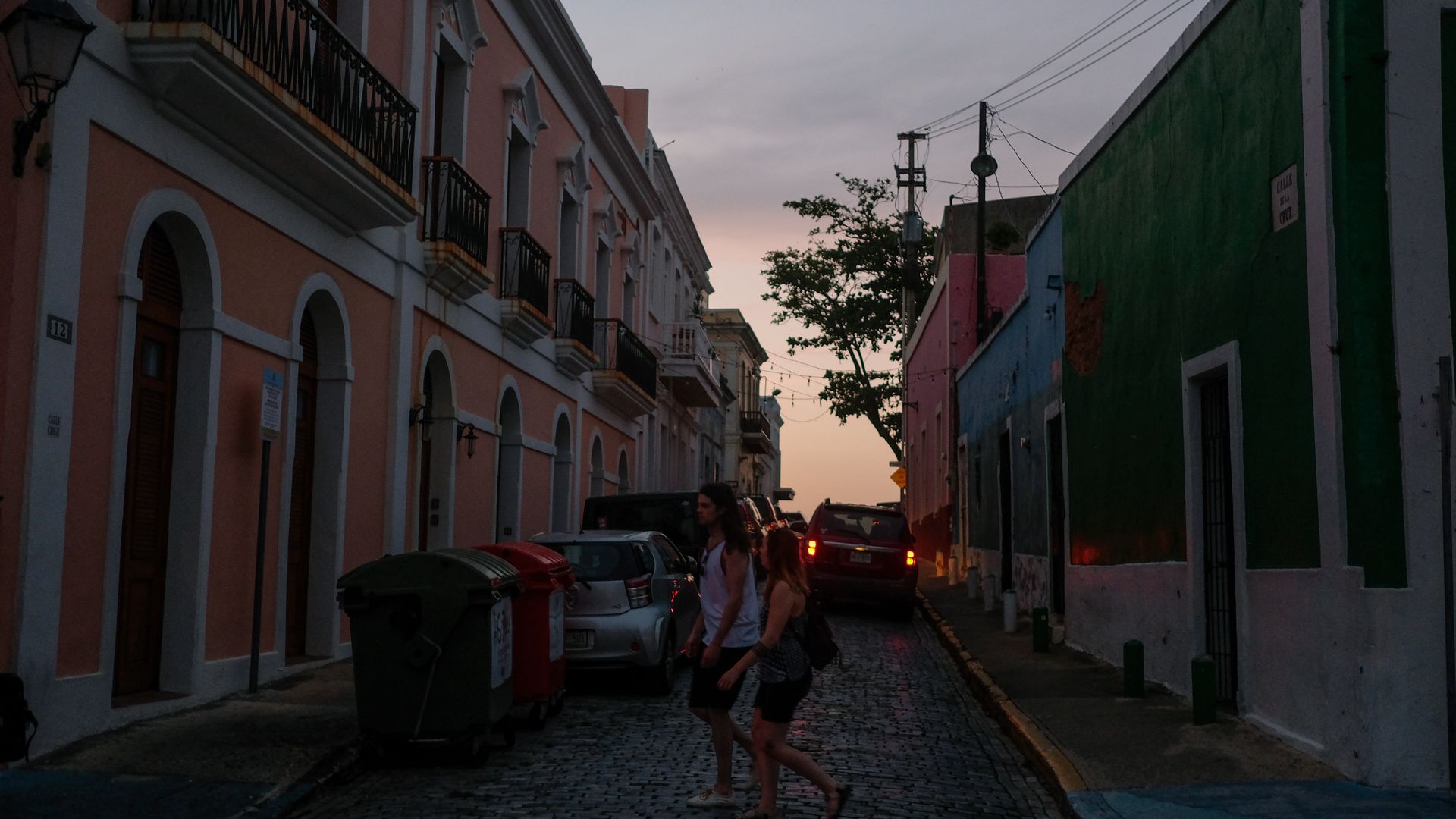 Tourists walk along a street with no electricity. 