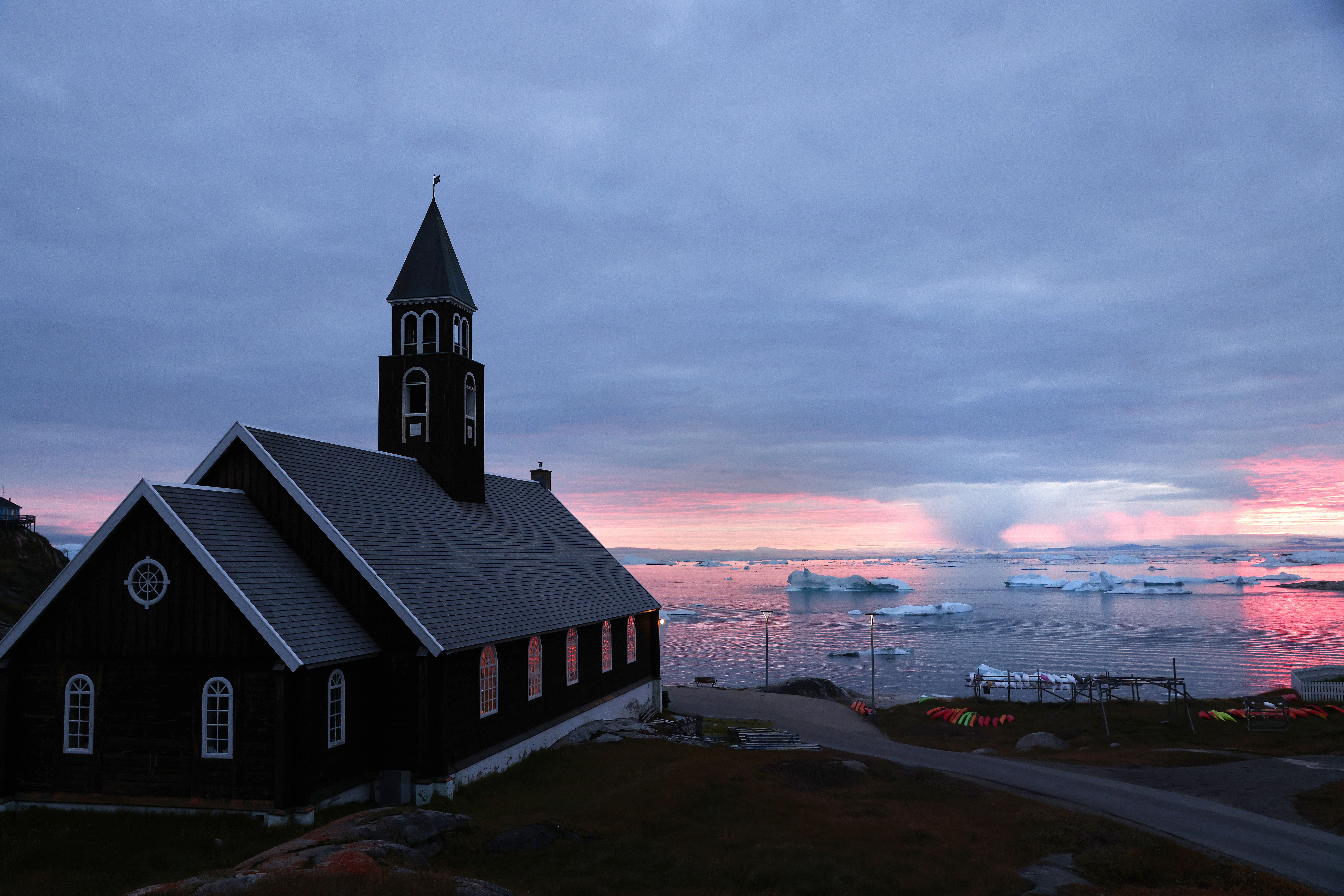 Rain falls beyond floating ice and icebergs and the historic Zion's Church on September 04, 2021 in Ilulissat, Greenland