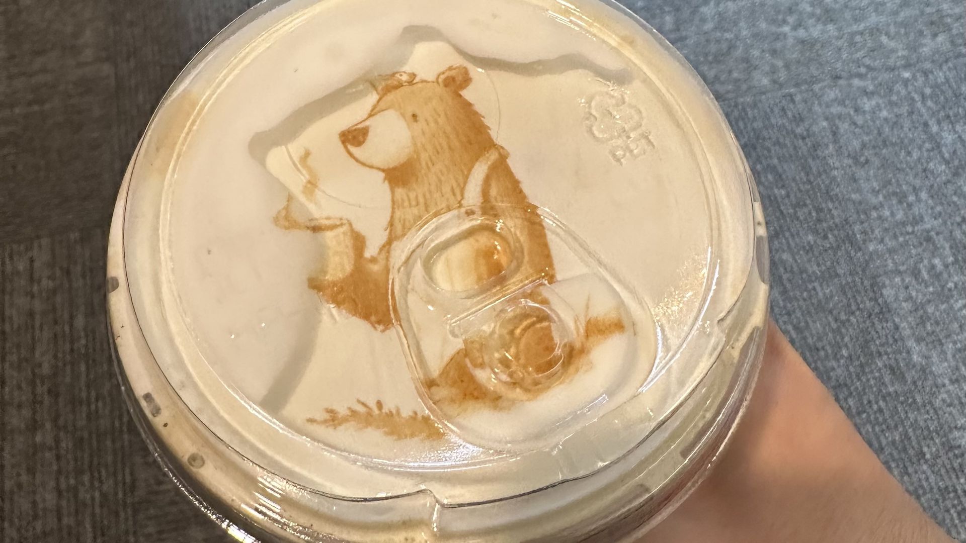 A cute little bear drinking coffee latte art 