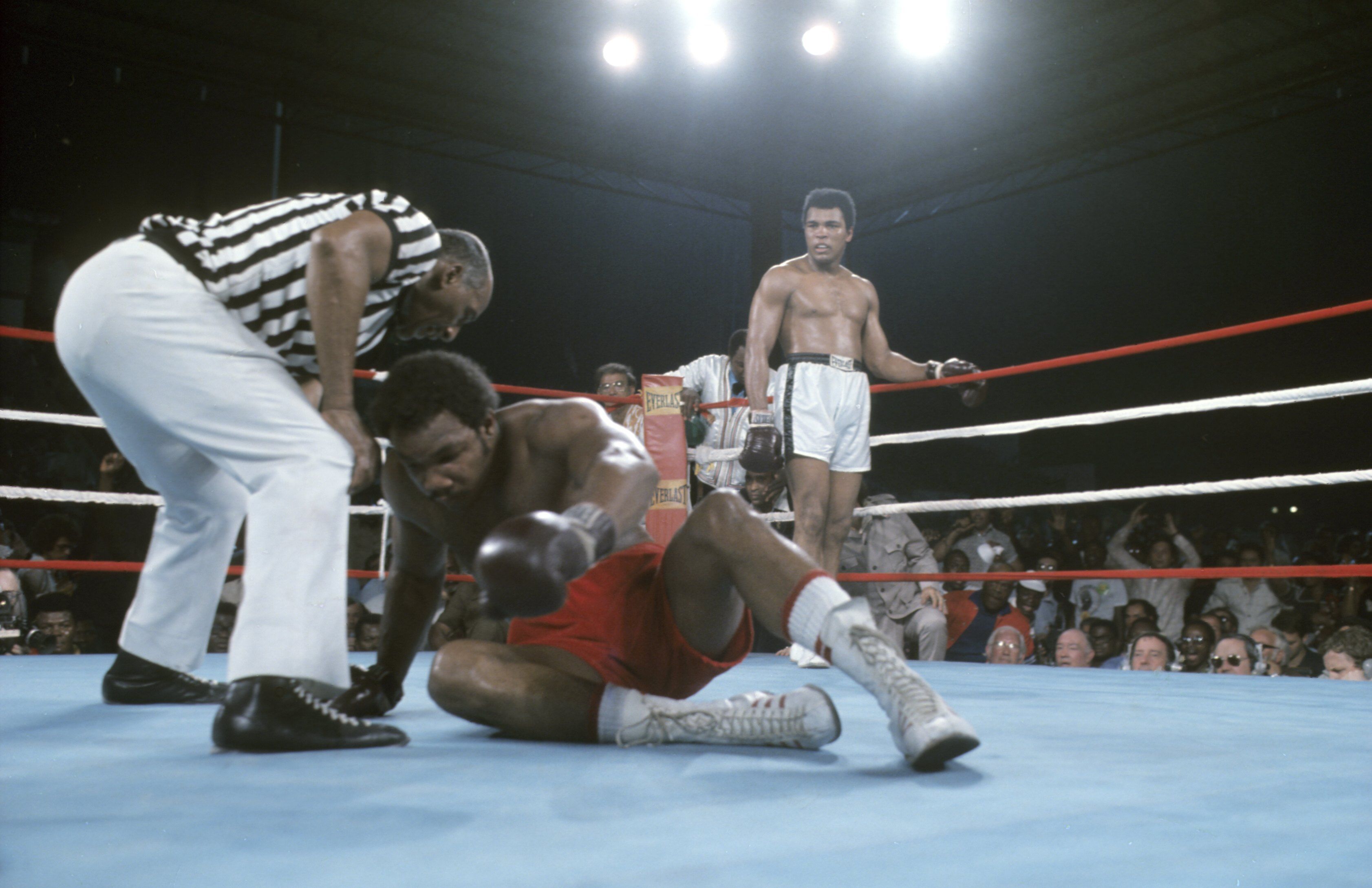  George Foreman tries to get off the canvas as referee Zack Clayton checks on him during the match against Muhammad Ali at 20th of May Stadium. Kinshasa, Zaire 
