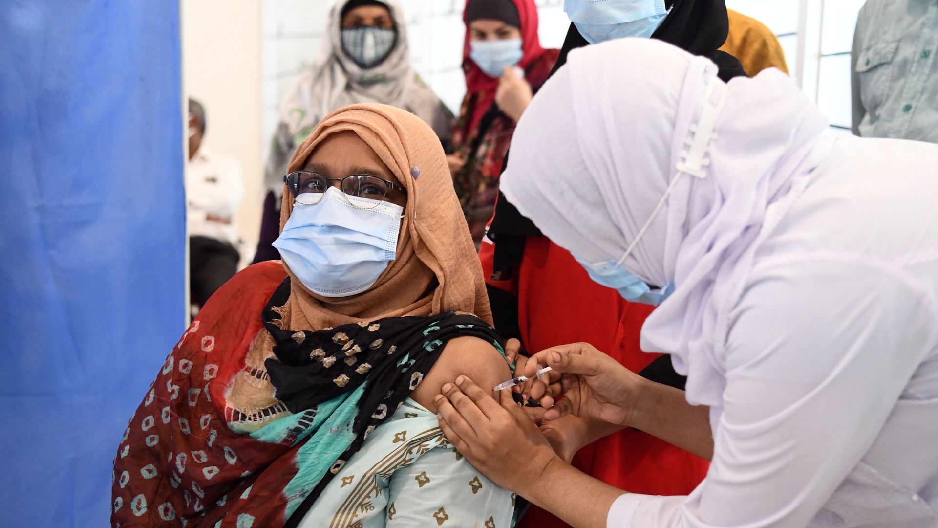 A woman receives a vaccine in her arm.