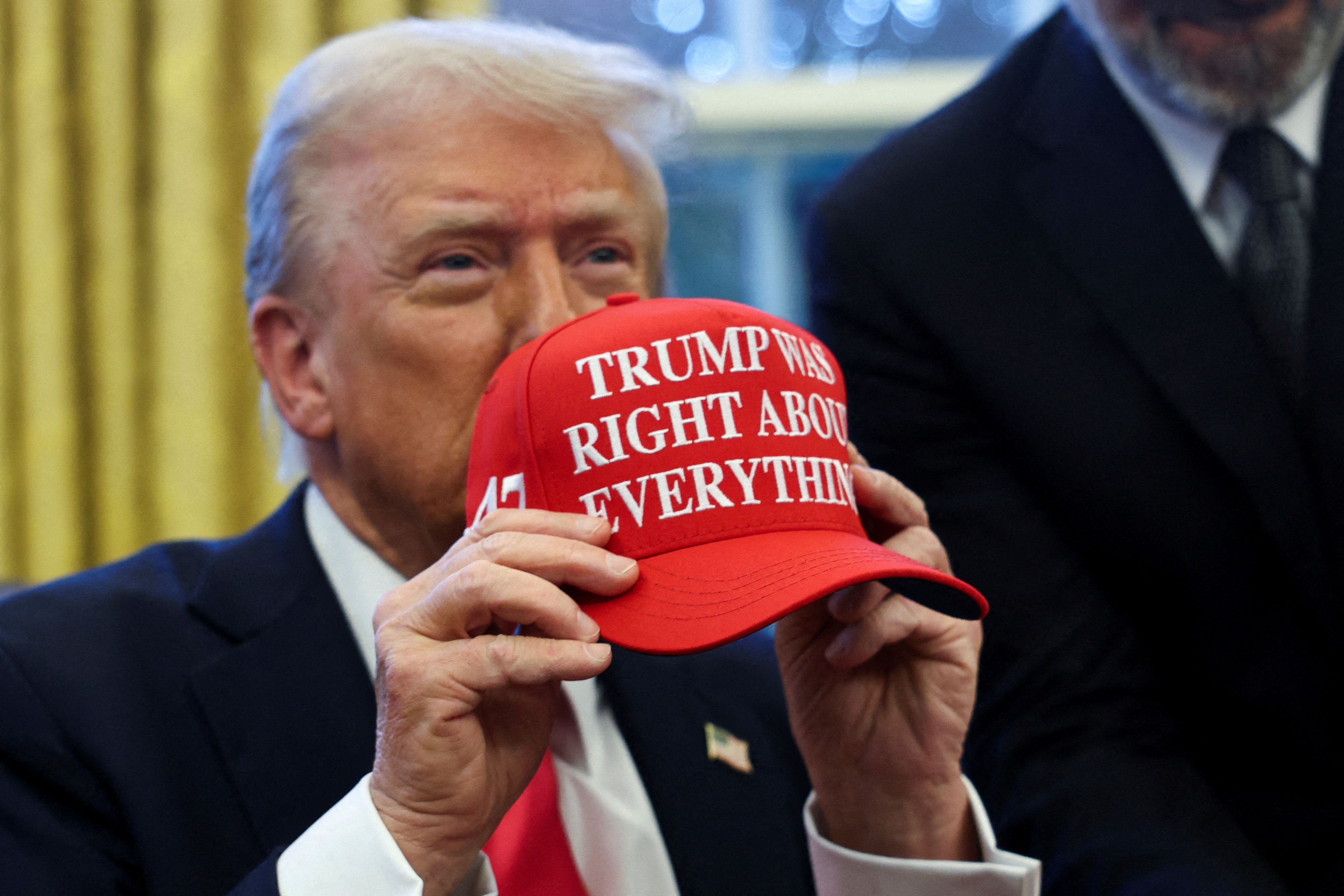 President Trump holds up a hat that says "Trump was right about everything" in the Oval Office yesterday.