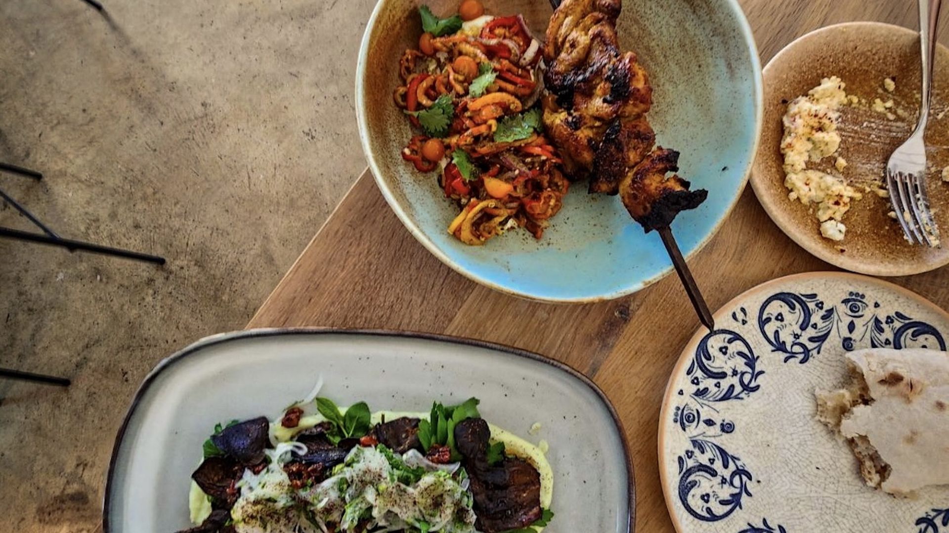 Four plates of food on a wooden table.