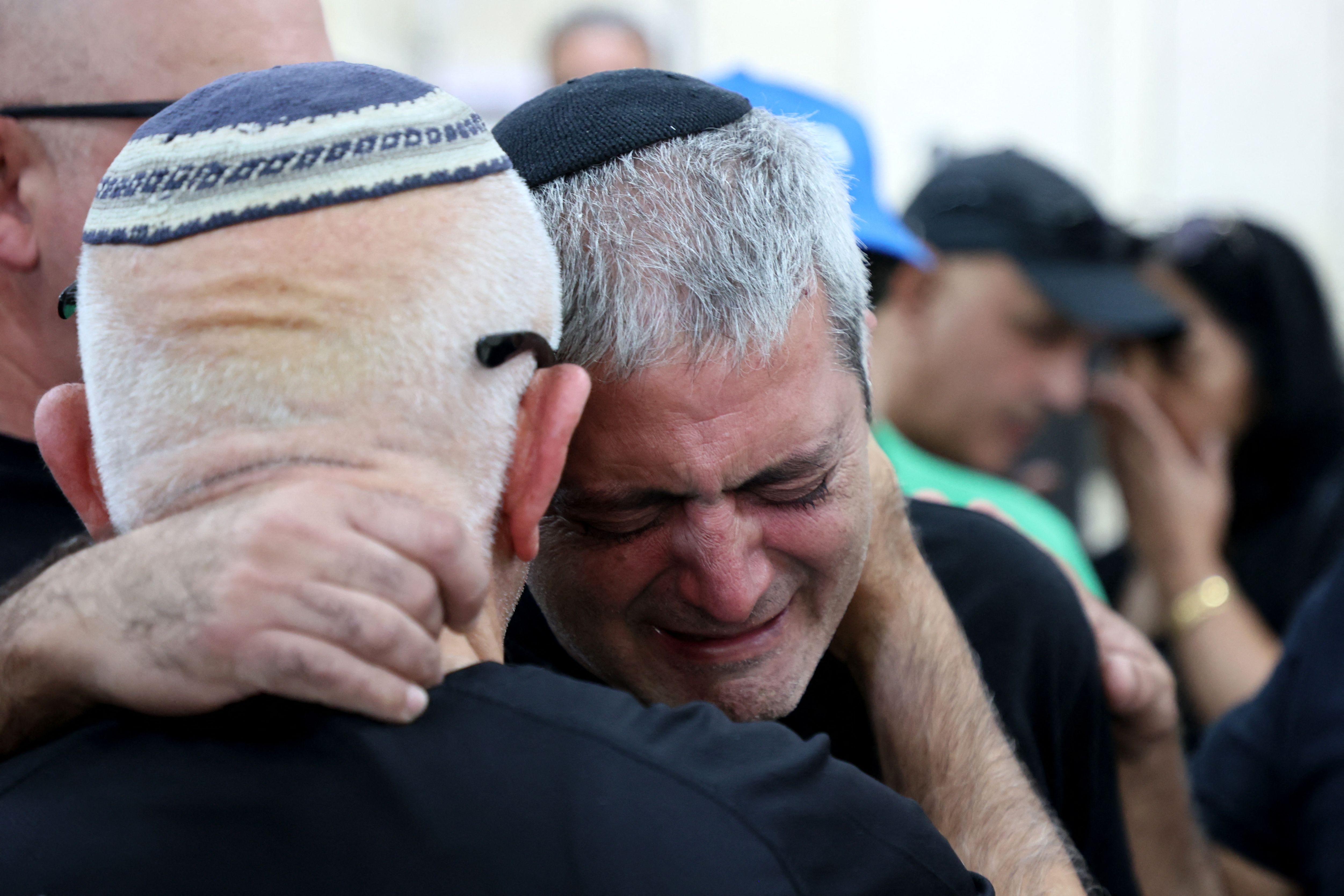 The father of Naor Hassisim is comforted during his son's funeral, a victim of the Kibbutz Kfar Aza attack last week by members of the Palestinian militant group Hamas, at a cemetery, in southern Israeli city of Ashdod
