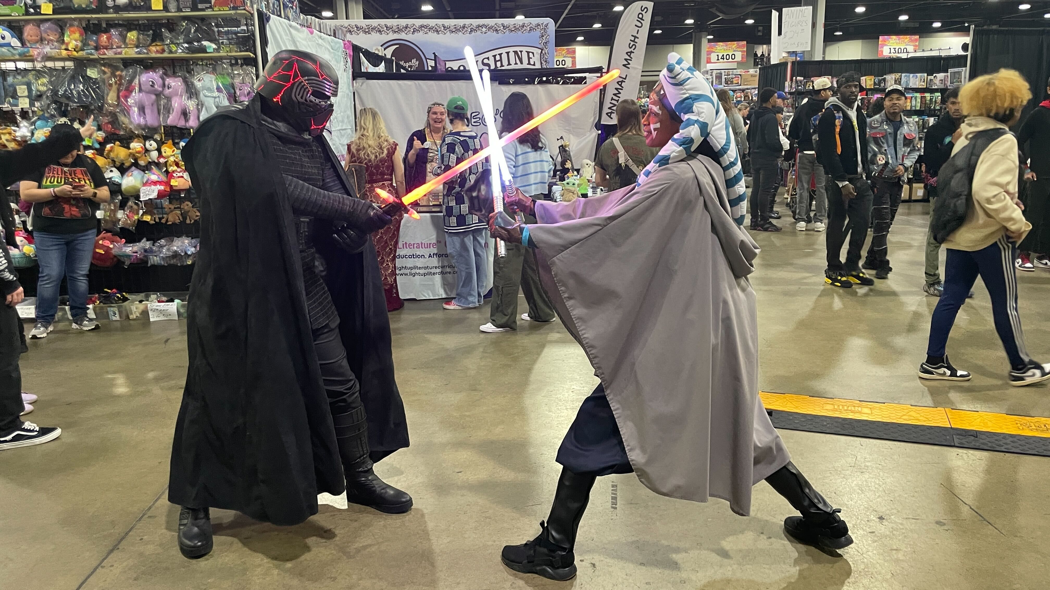 Cosplayers dressed as  the Star Ways characters Kylo Ren and Ahsoka Tano in a lightsaber battle.