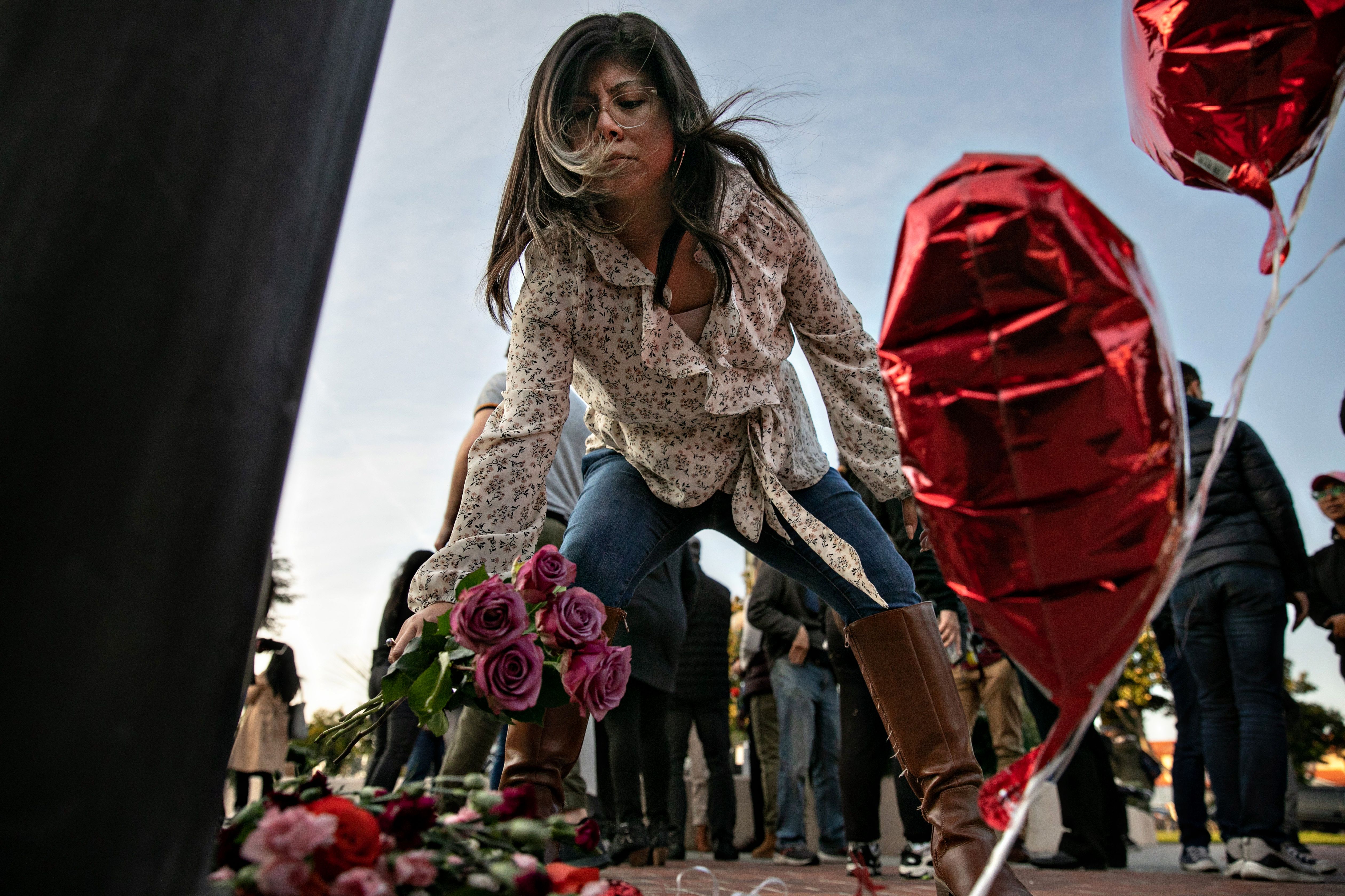  A woman places flowers at a memorial where community members gathered for vigil to the people who were killed by a gunman at a dance studio on Sunday, Jan. 22, 2023 in Monterey Park, CA. 