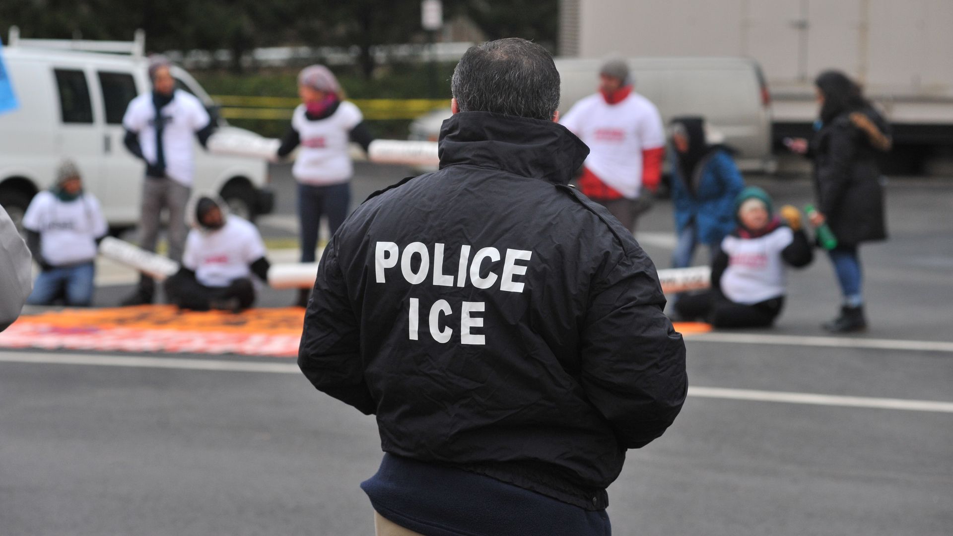 An ICE officer stands in front of protestors