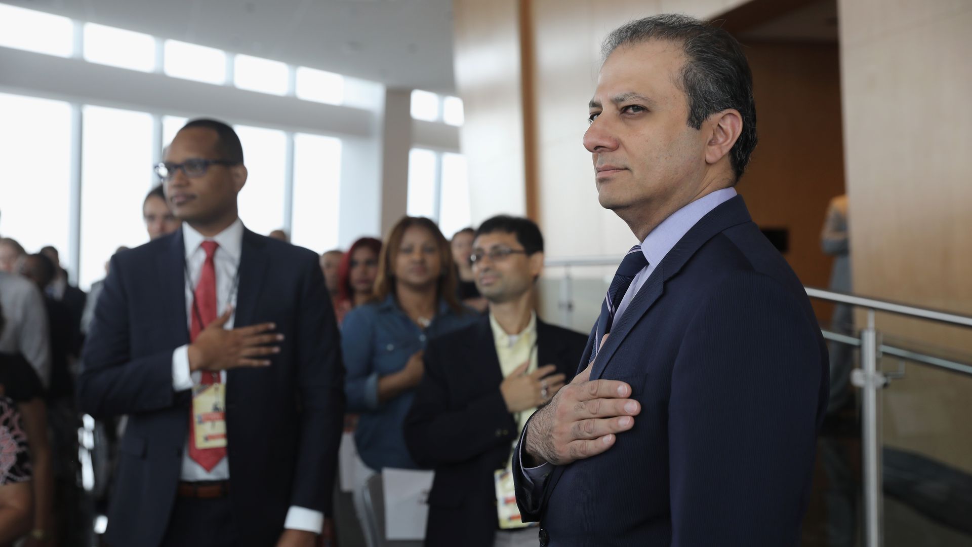 Preet Bharara stands with his hand over his heart.