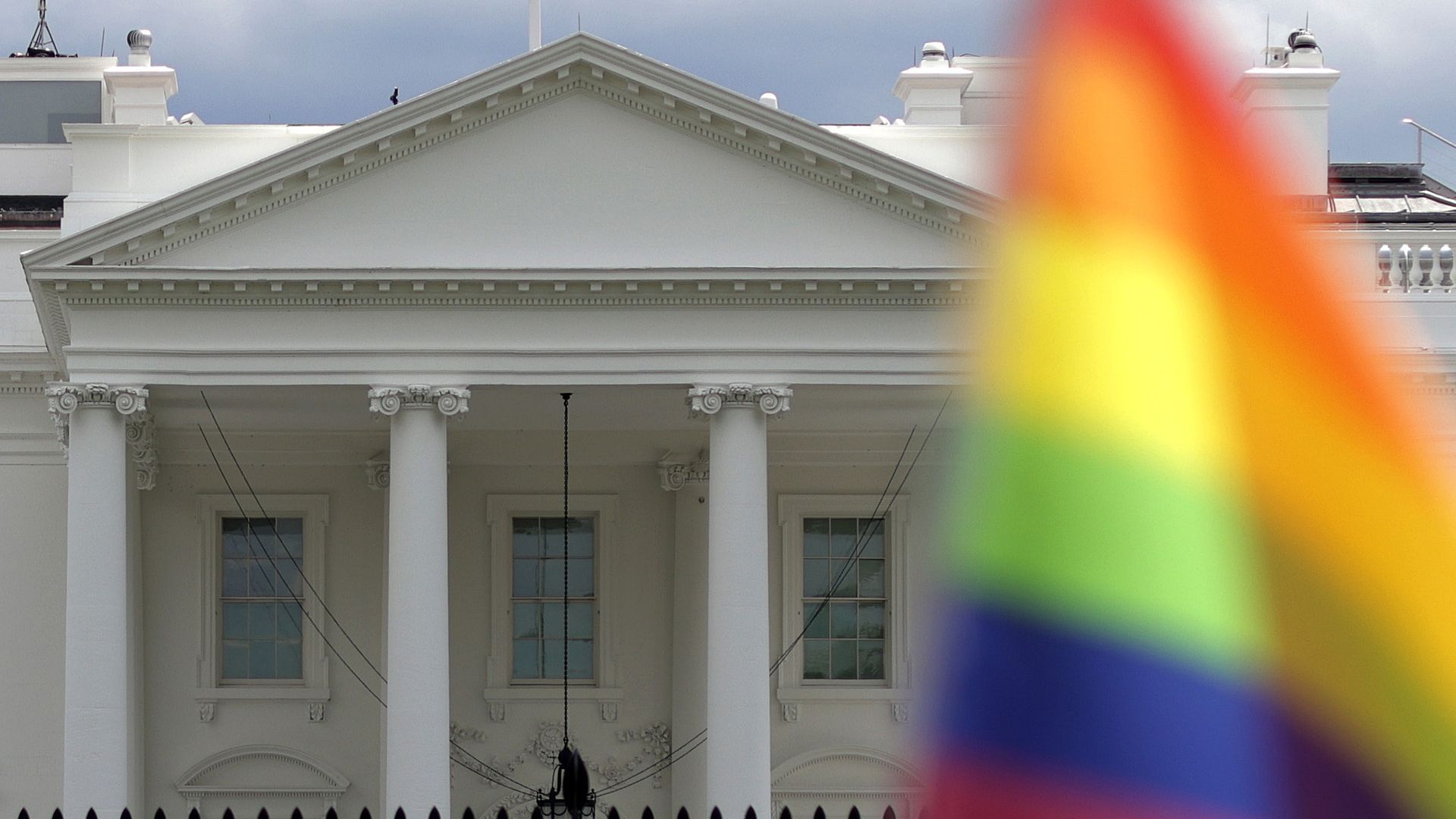 Picture of the White House with a rainbow flag in front of it