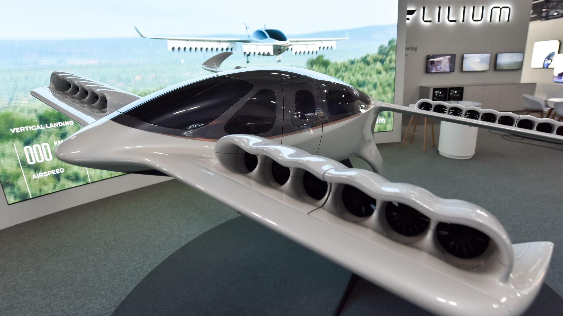 A small white electronic airplane with electric motors on its front and back wings.