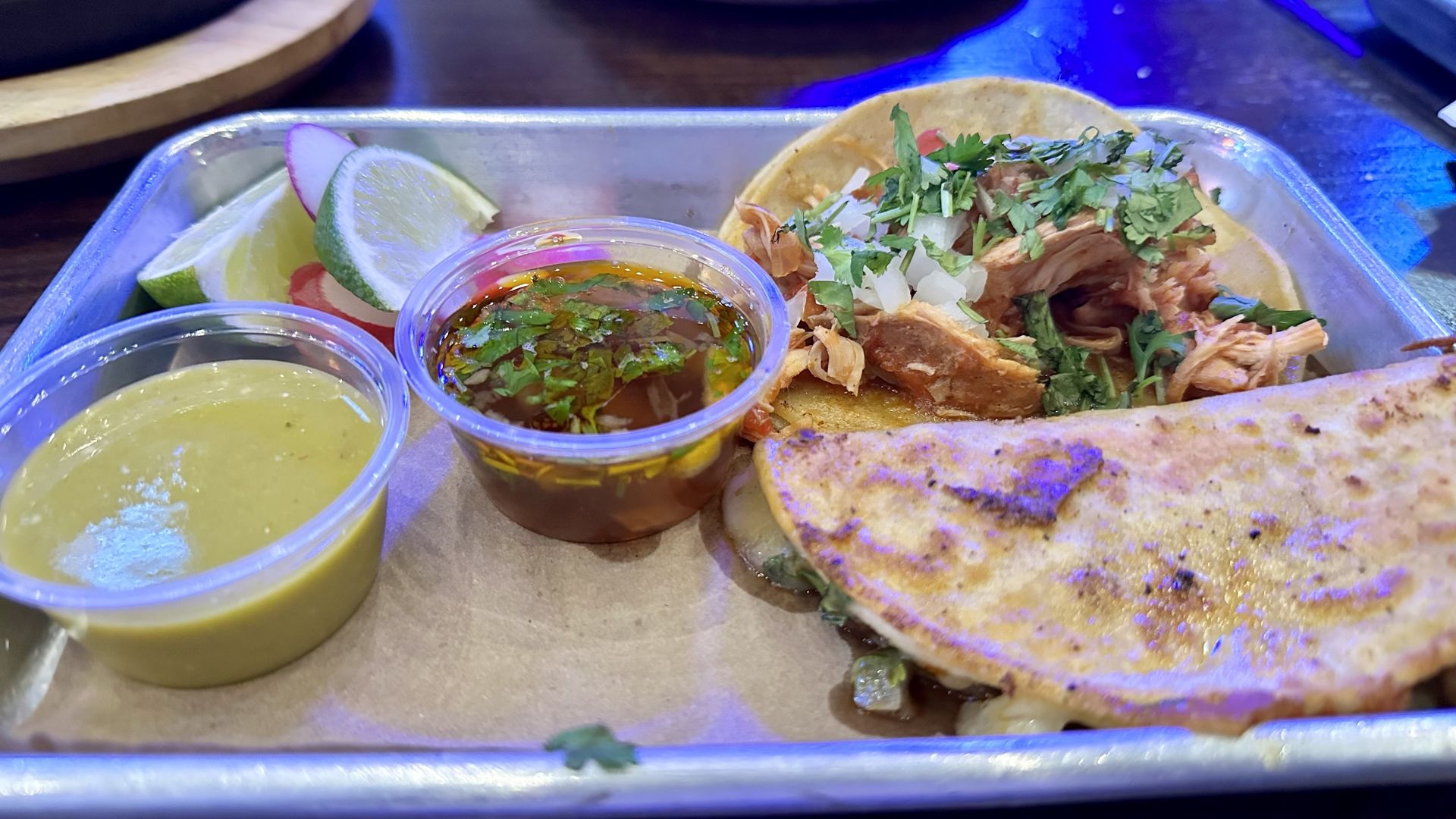 Two tacos with sides of consommé and salsa