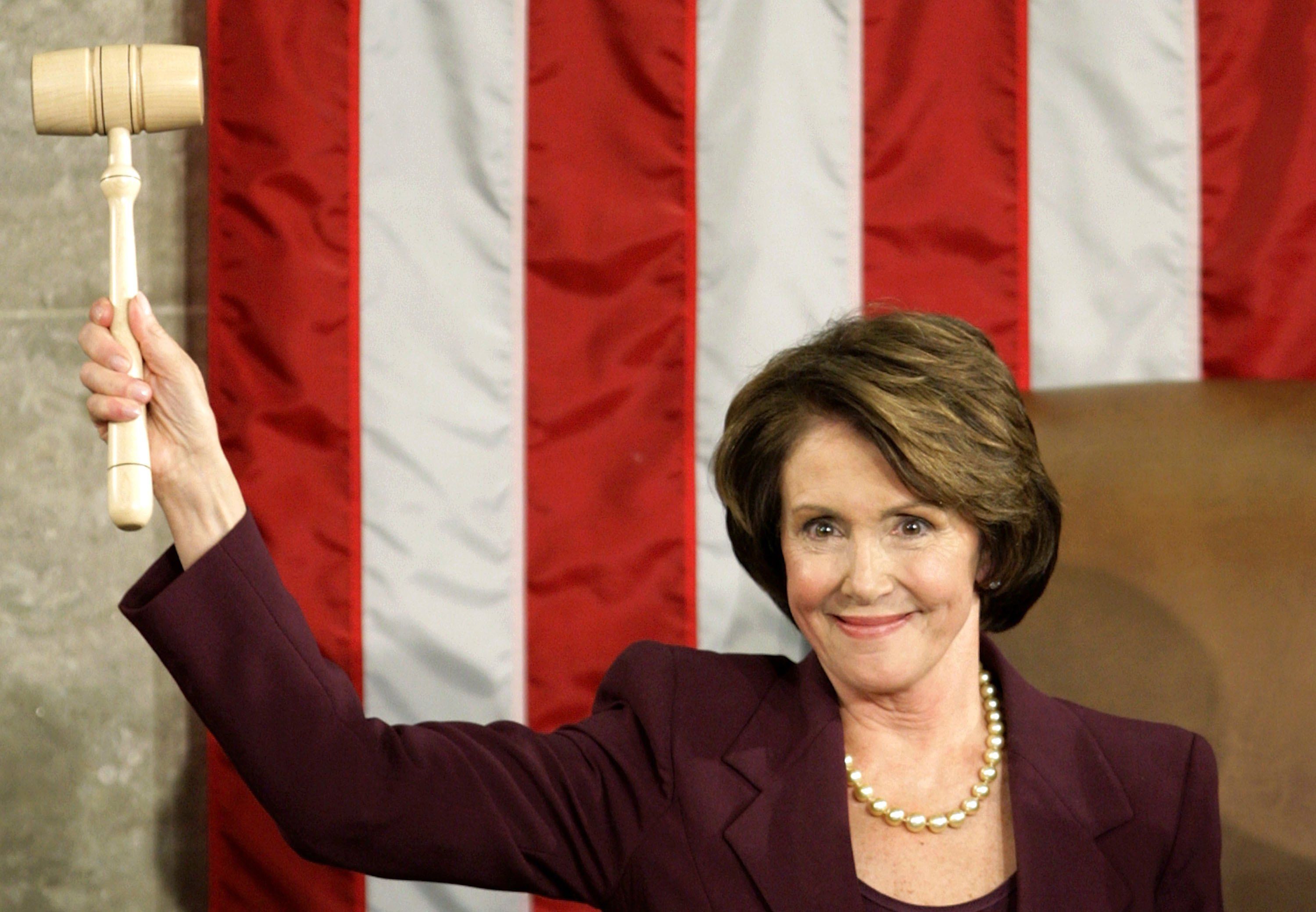 Nancy Pelosi, wearing a dark blazer, raises the Speaker's gavel in the House chamber after being sworn in as the first female Speaker in 2007.