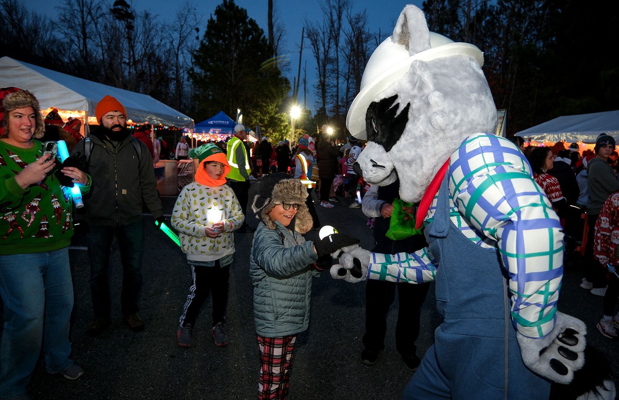 A raccoon mascot giving a fist bump to a kid