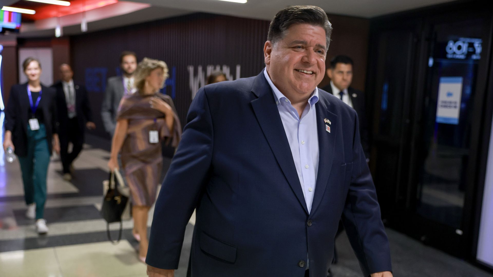 Photo of a man walking past cameras in a hallway
