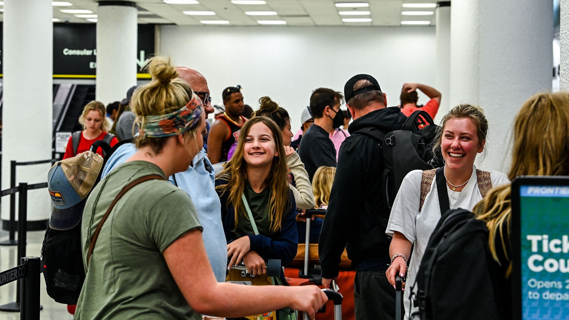 A mix of masked and unmasked people wait in a security line at Miami International Airport.