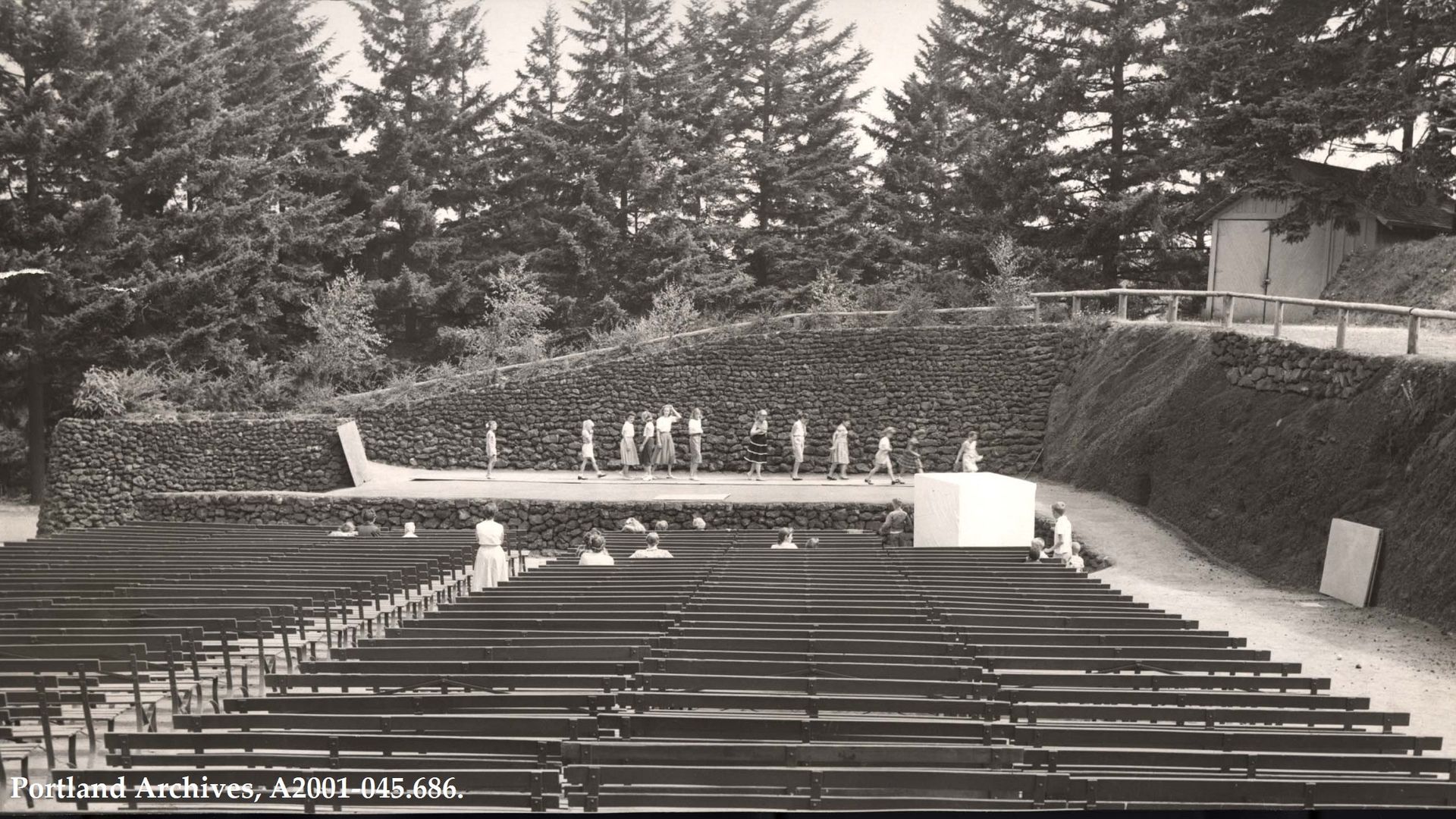 An archival photo of people standing on a stage and preparing for a dance recital. 