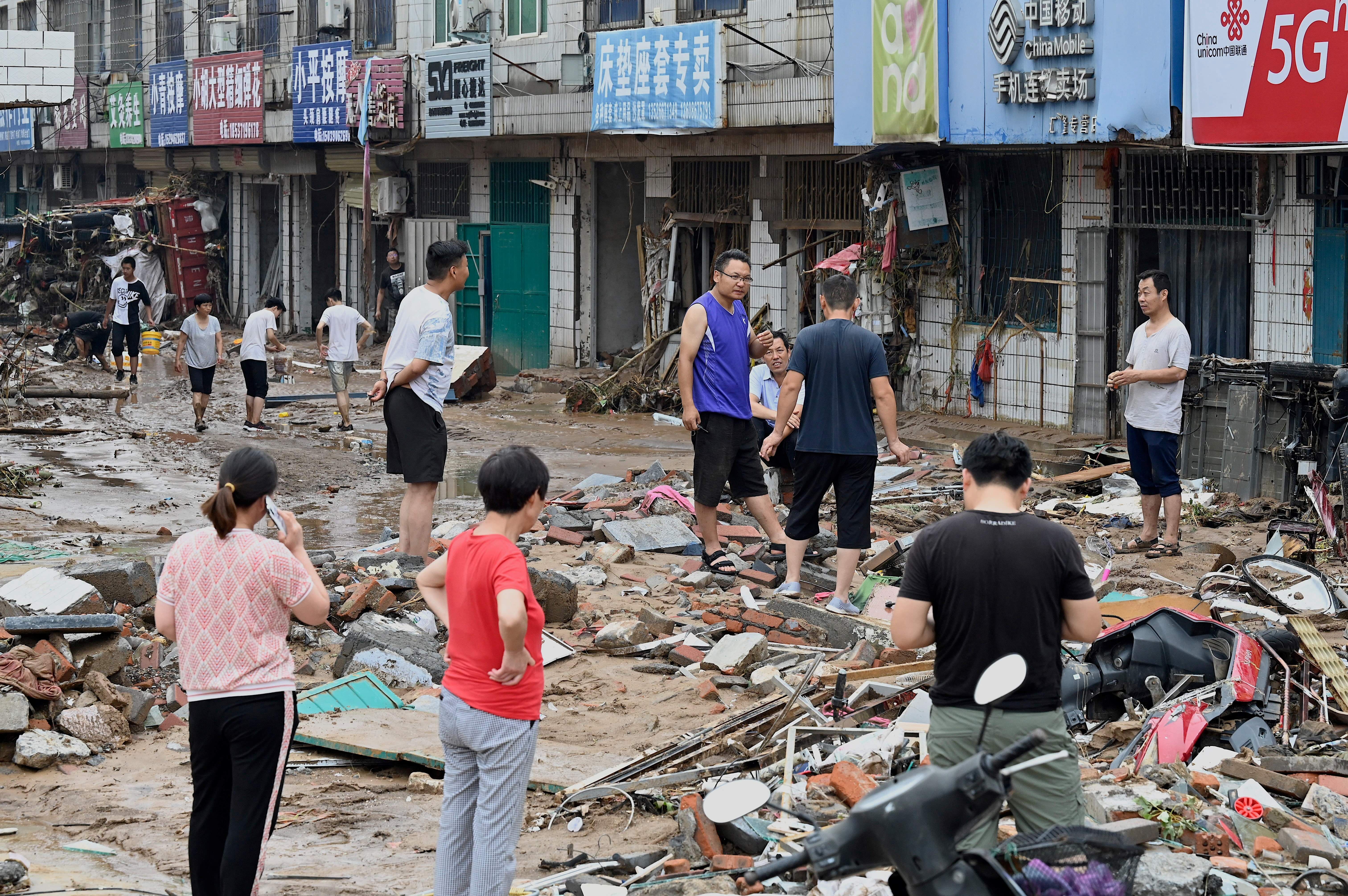 People talking in a destroyed street in Gongyi on July 22.