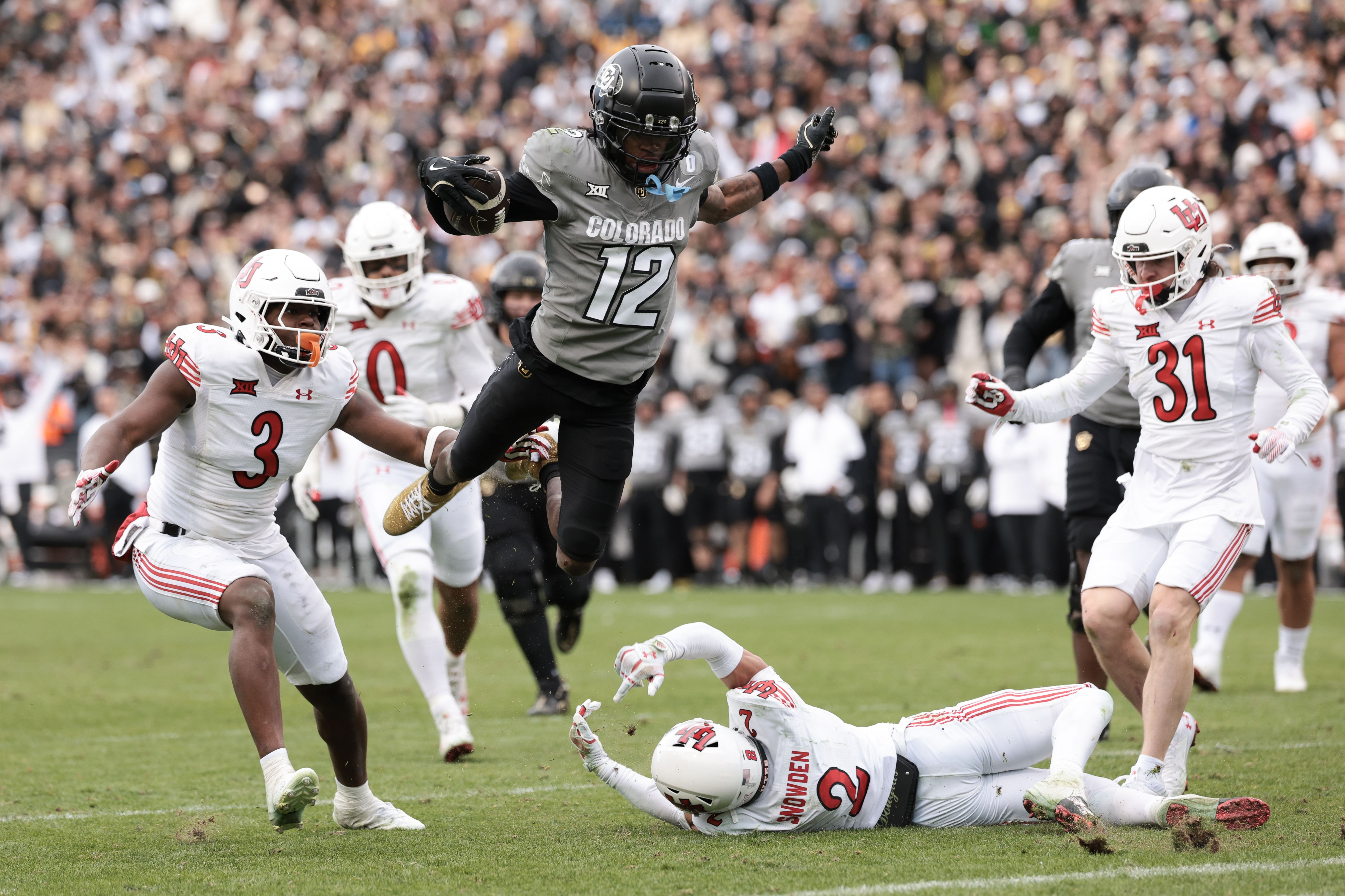 Photo of a football player jumping over a tackler.