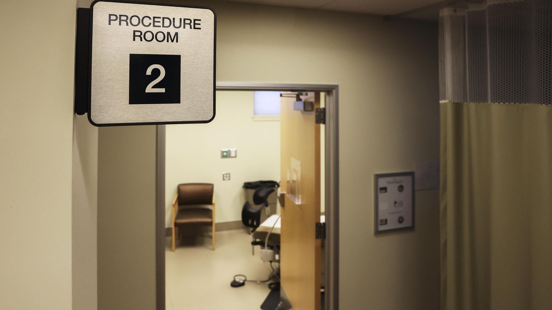 Photo of a procedure room in a hospital, showing a bed and chair