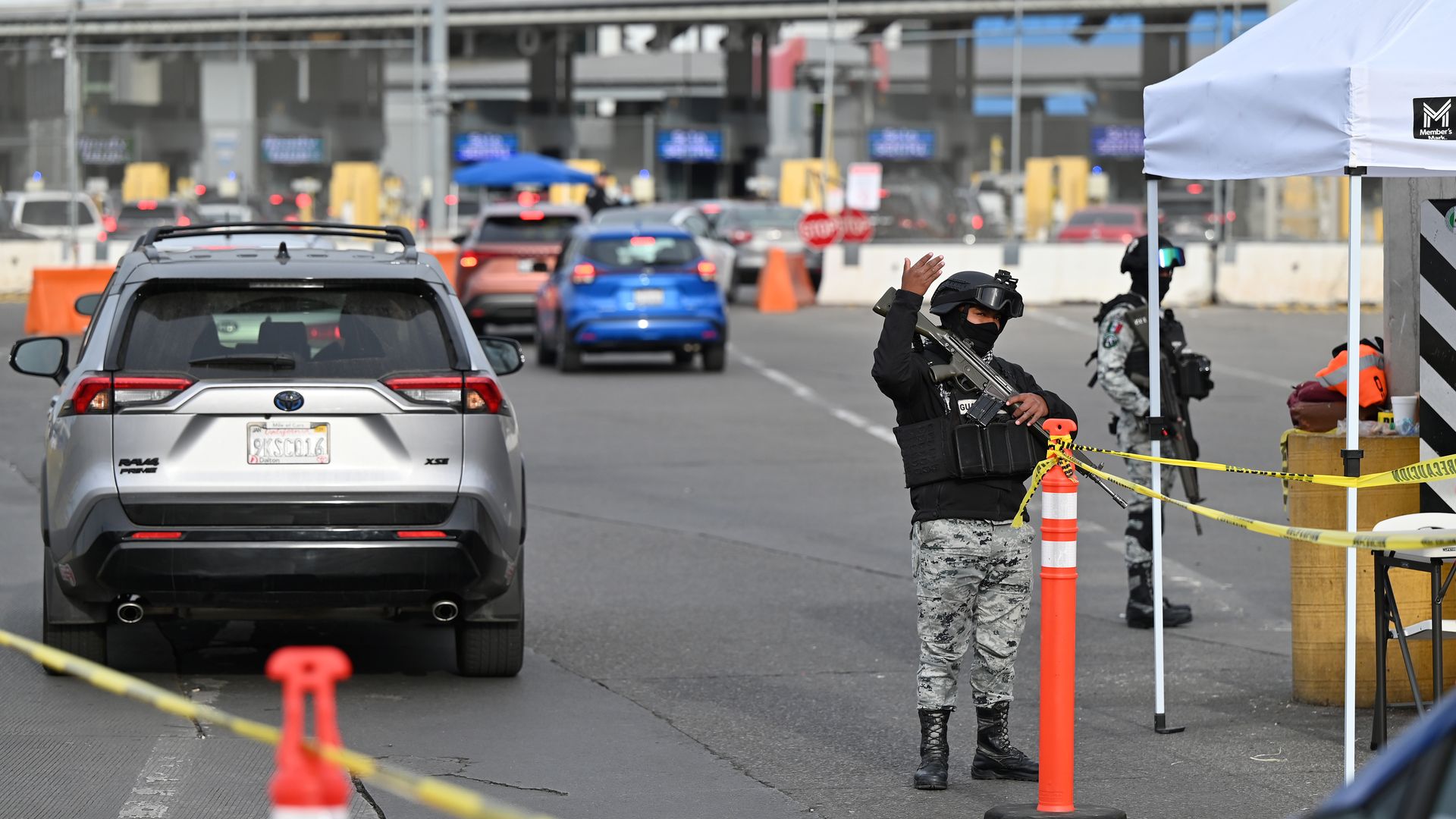 an armed member of Mexico's national guard flags a car through at a border crossing in Tijuana, Mexico