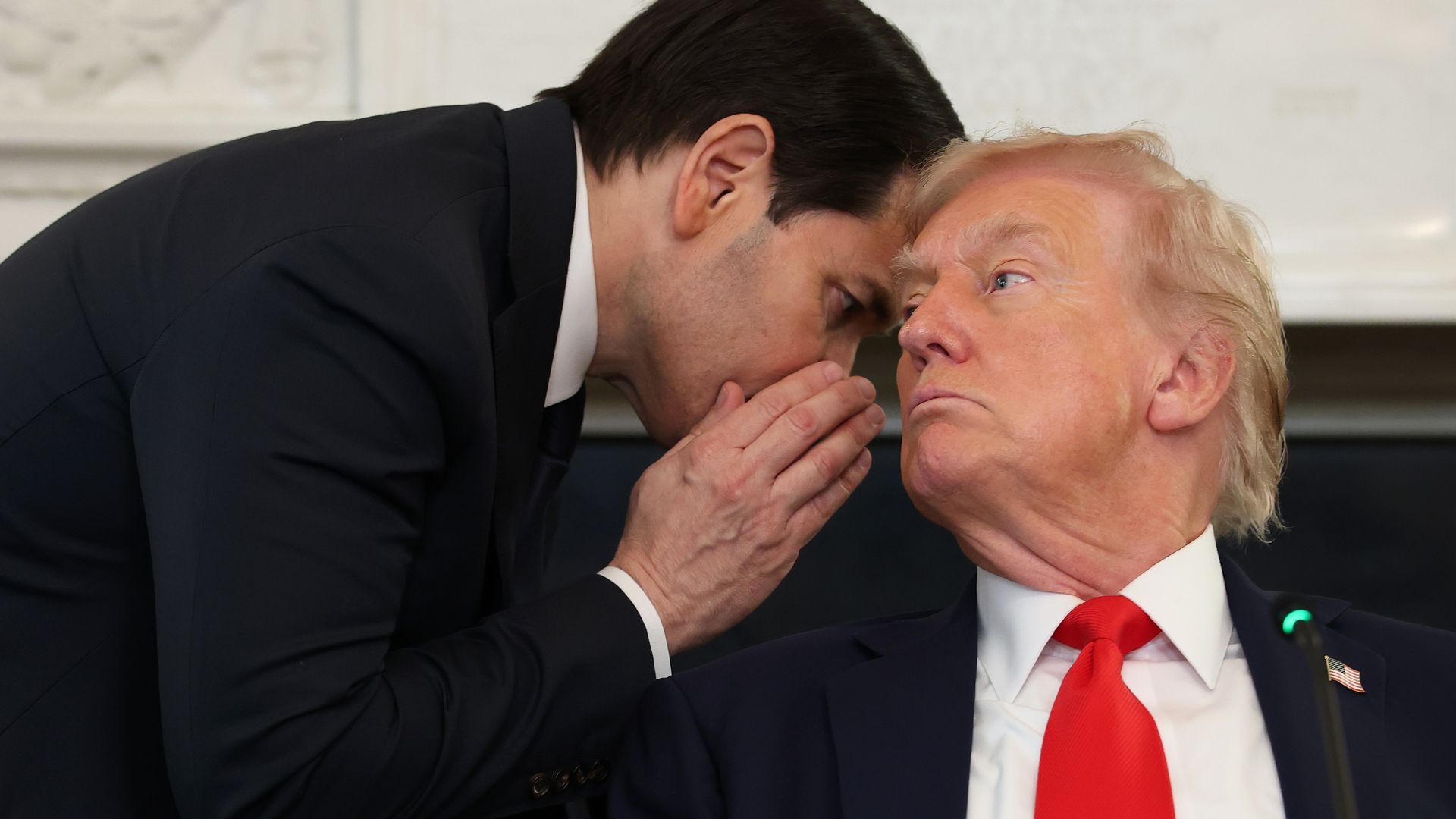 Man whispers into man's ear