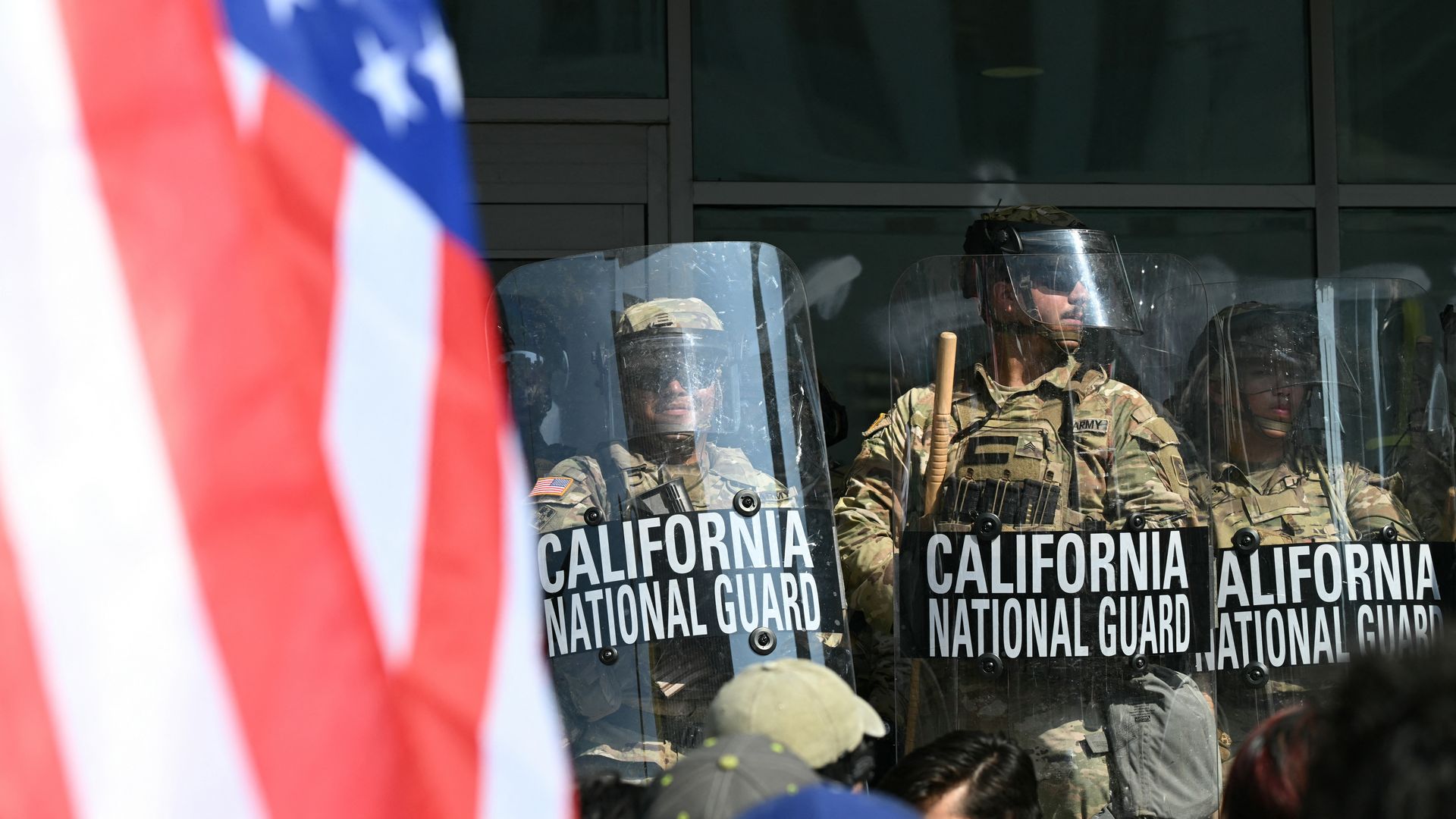  A demonstrator holds an upside down US flag as they face California National Guard members standing guard outside the Federal Building during a protest in response to federal immigration operations in Los Angeles, on June 9, 2025. 