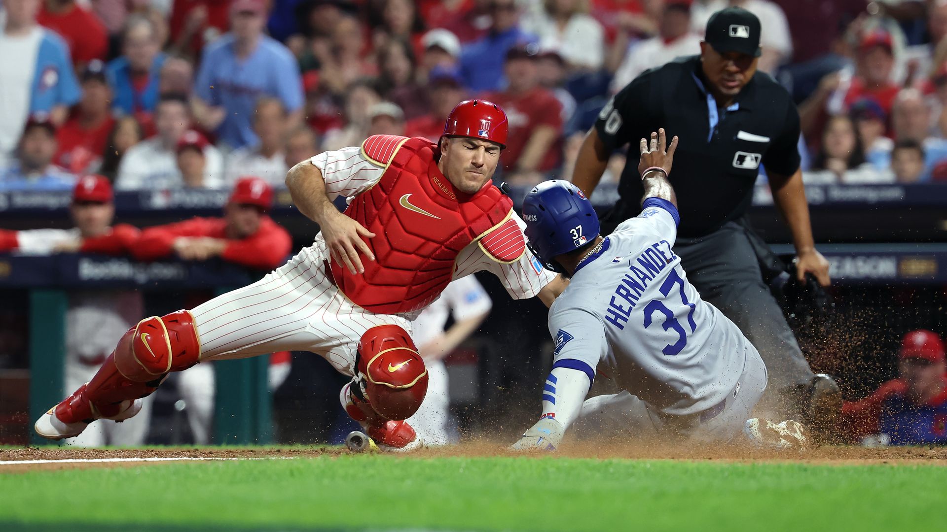 The Dodgers' Teoscar Hernandez slides past Phillies catcher J.T. Realmuto at home plate during the seventh inning of Game 2 of the NLDS.