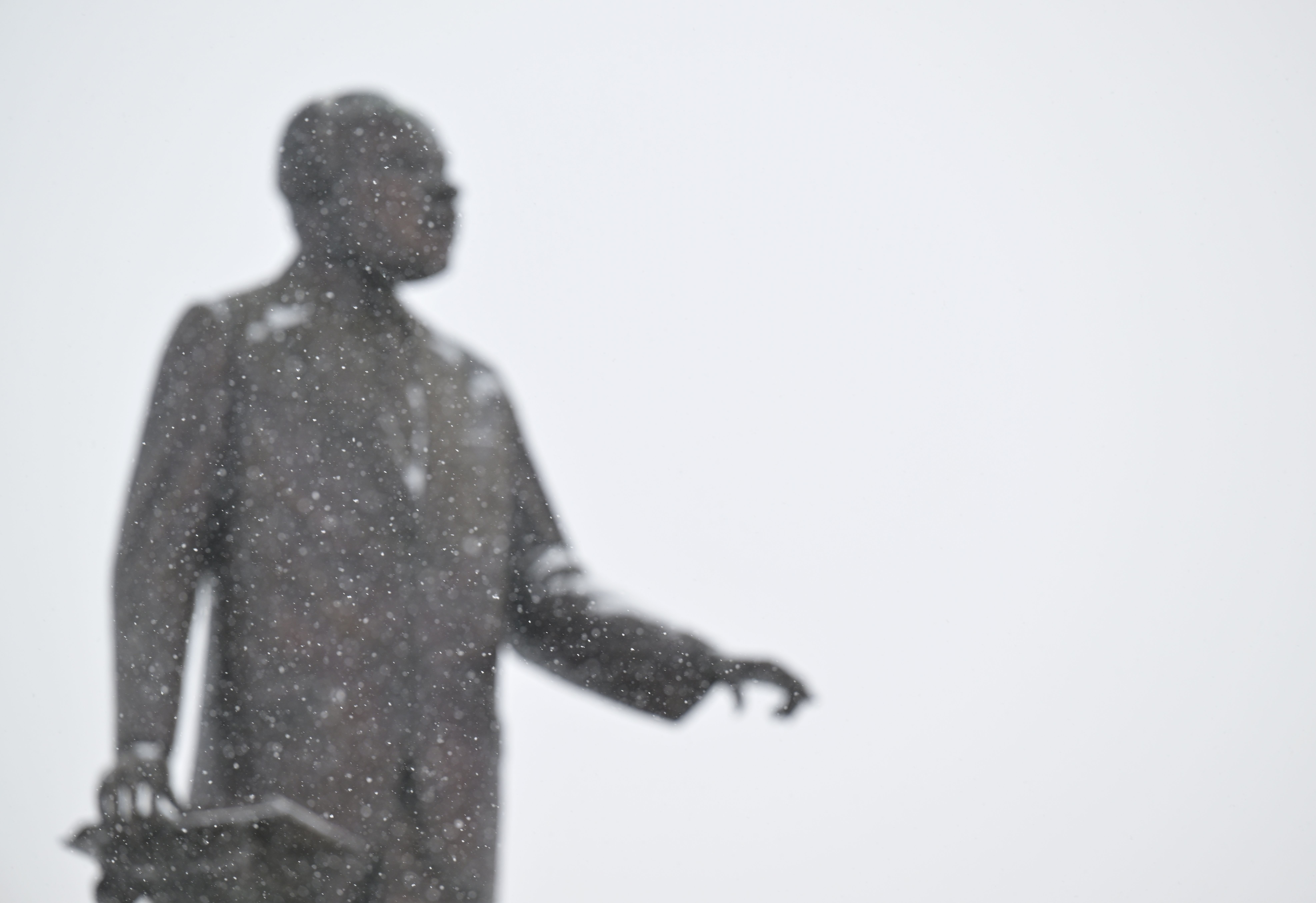 Snow falls in front of a statue of Martin Luther King Jr. by Ed Dwight at City Park on Dr. Martin Luther King Jr. Day in Denver, Colorado on January 15, 2024. 