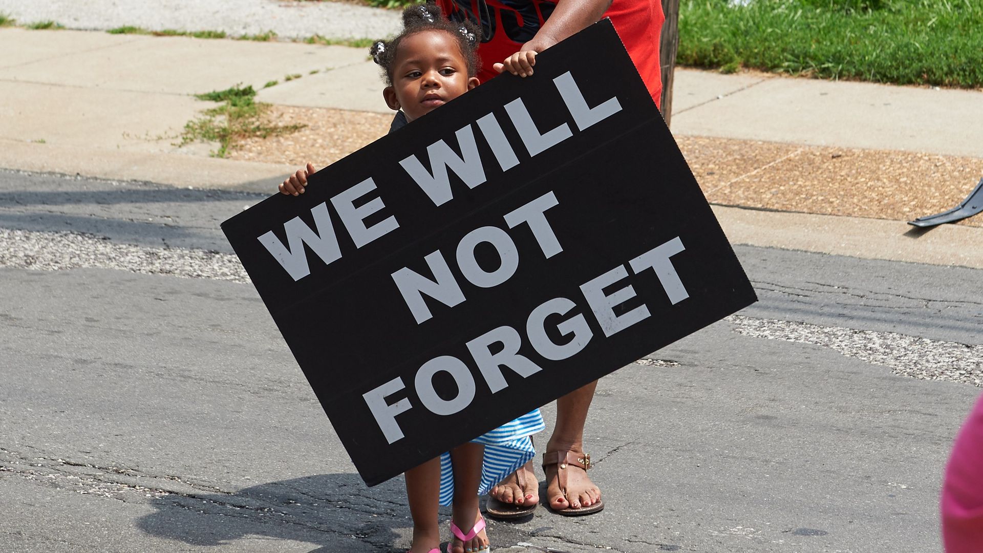 A young girl holds a sign on August 8, 2015 in Ferguson, Missouri. As the embattled community celebrates the one-year anniversary of the shooting of Michael Brown Jr. by a Ferguson police officer.