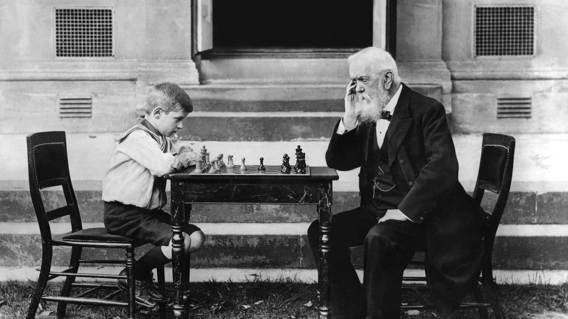 Young boy playing a game of chess with an old man. 