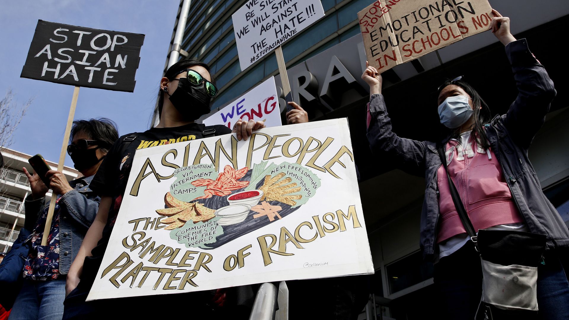 Photo of a person holding a sign that says "Asian people, the sampler platter of racism"