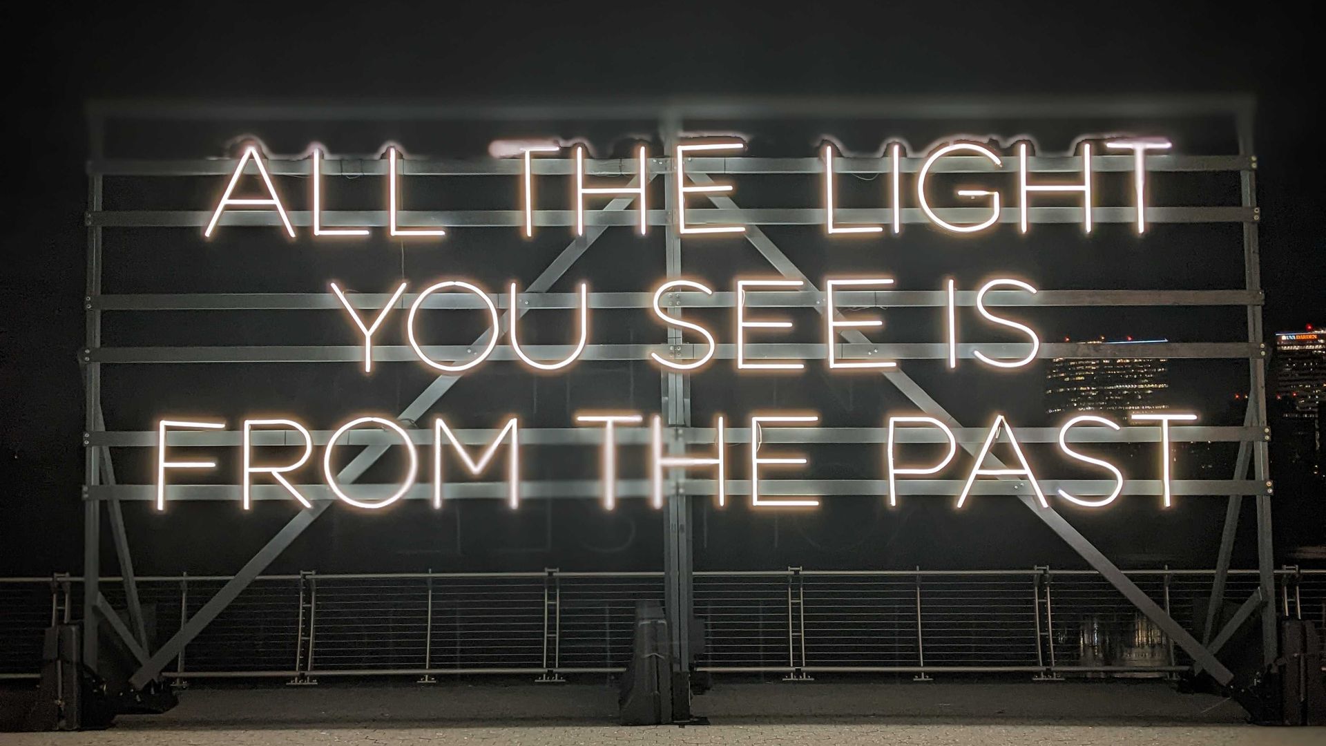 An art illustration using yellow neon saying "all the light you see is from the past"