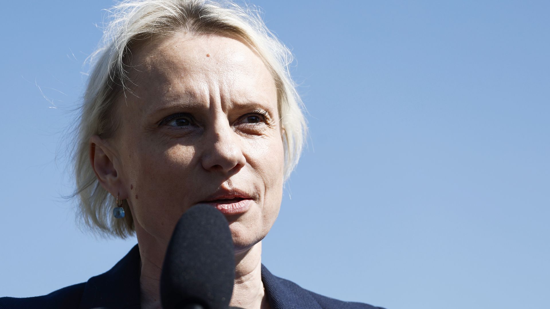 Rep. Victoria Spartz speaking into a microphone under a clear blue sky.