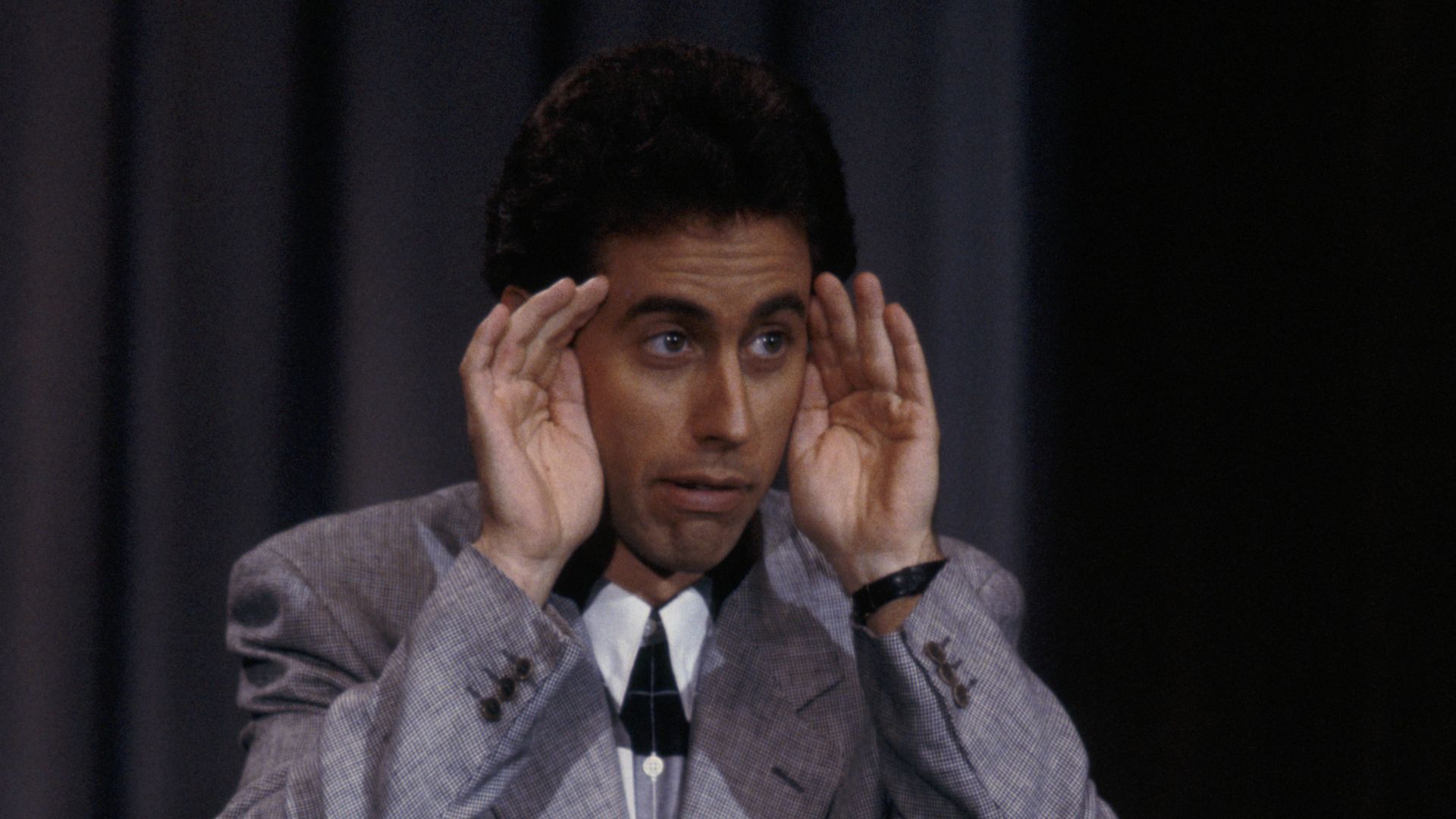 Jerry Seinfeld performs standup comedy on stage.