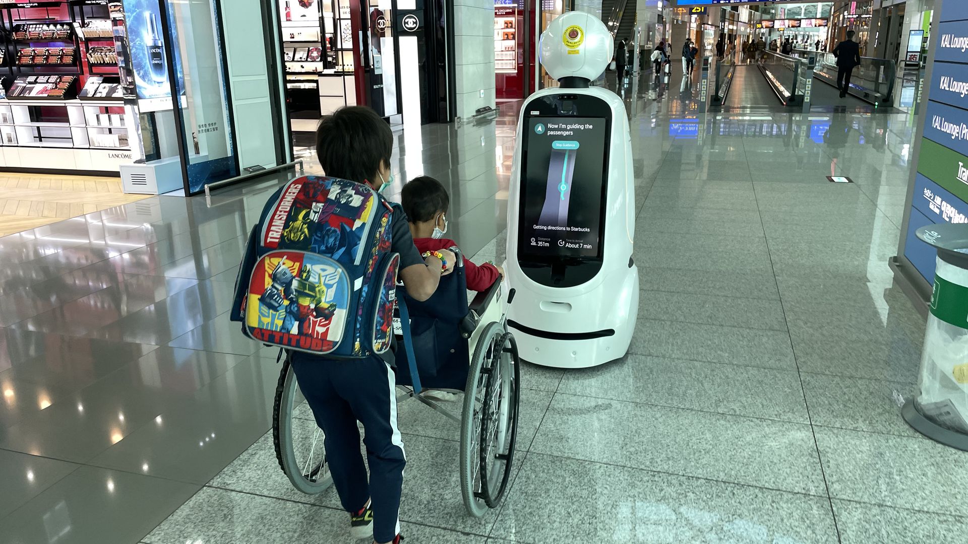 Airport passengers follow a smart robot that gives them directions.