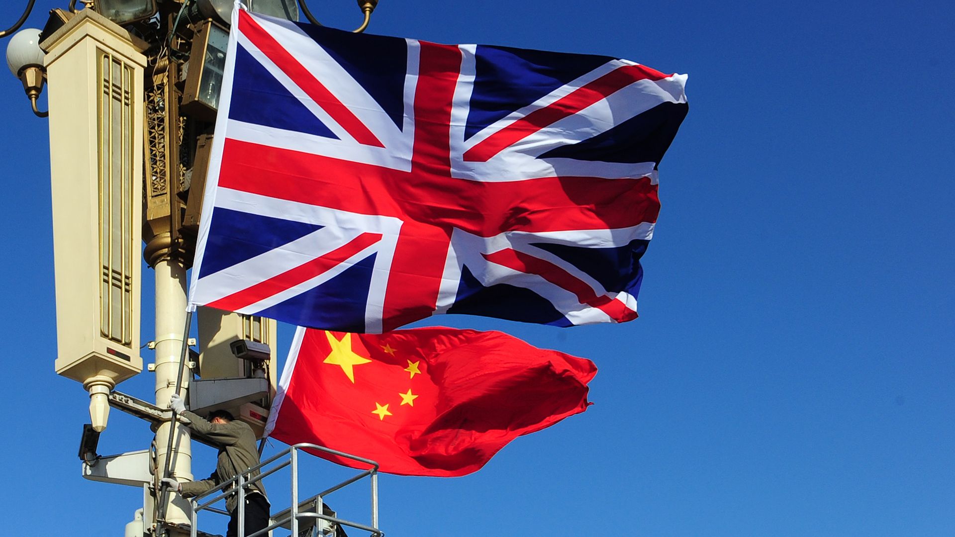 The Union Jack being hoisted next to the flag of the People's Republic of China.