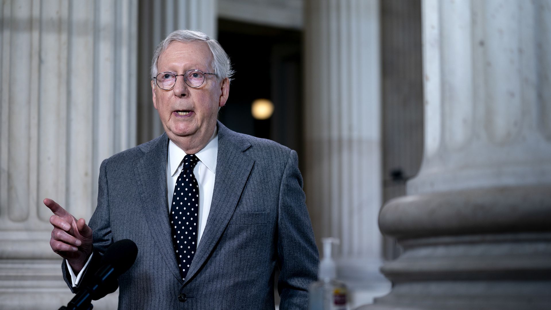 Photo of Mitch McConnell speaking during a television interview with one hand raised