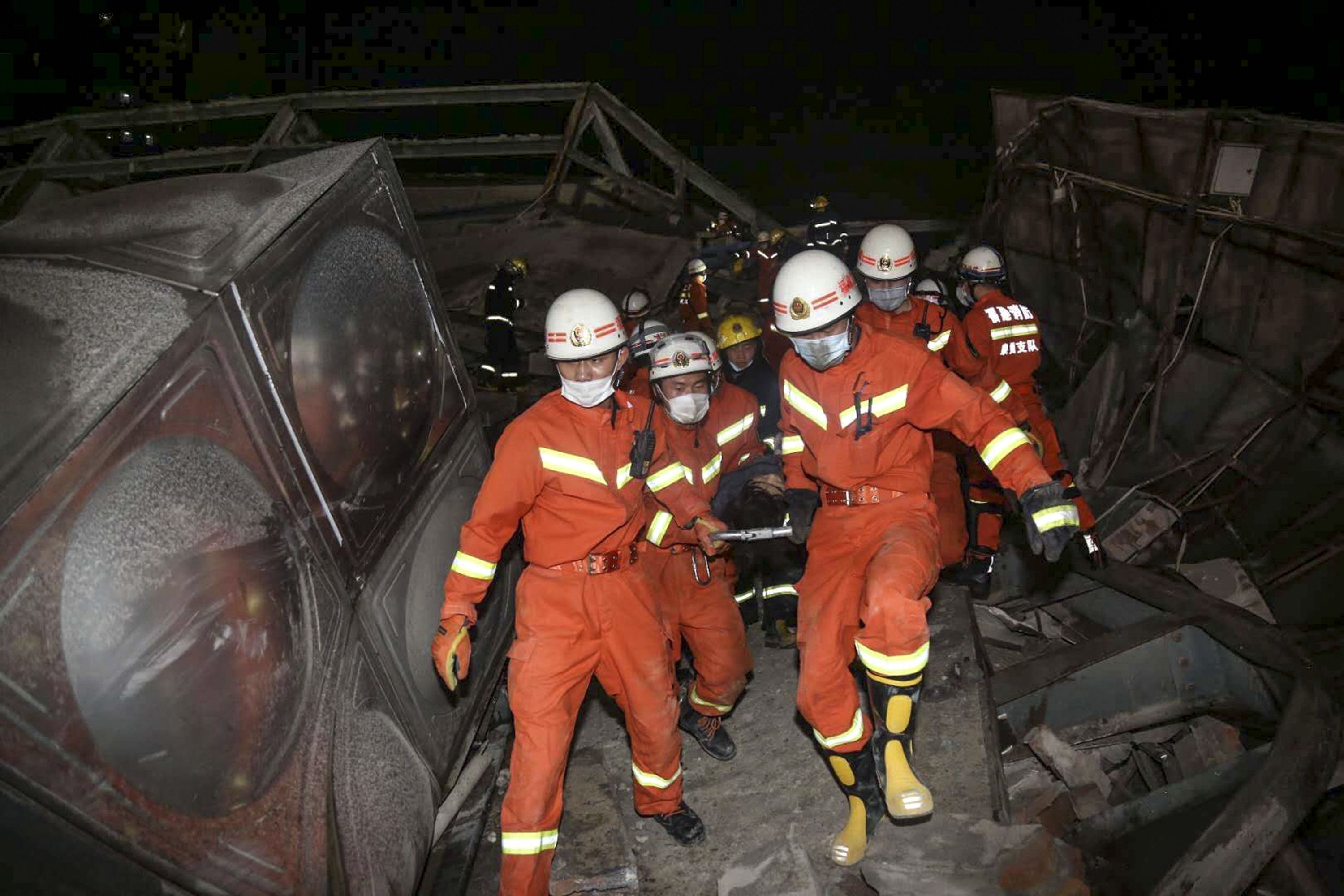 In this image, a group of emergency workers walk through the rubble