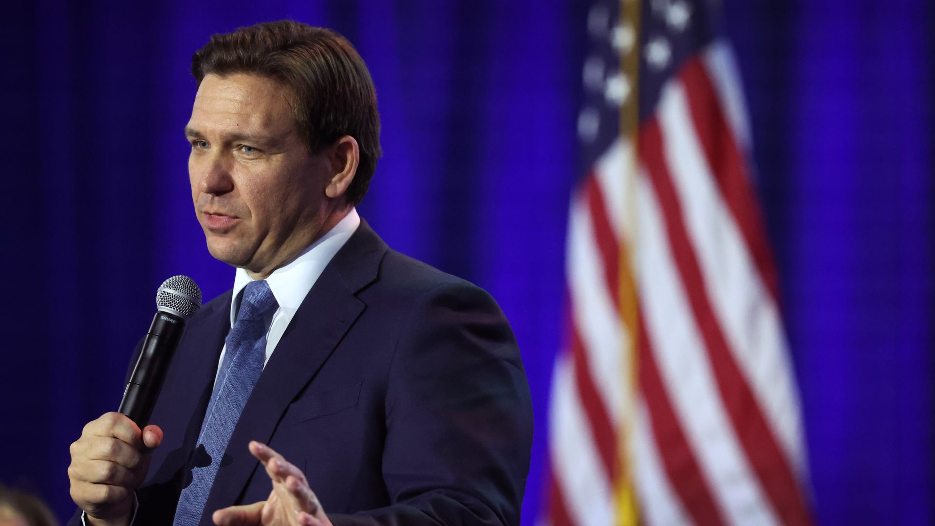Photo of Ron DeSantis speaking into a microphone on stage