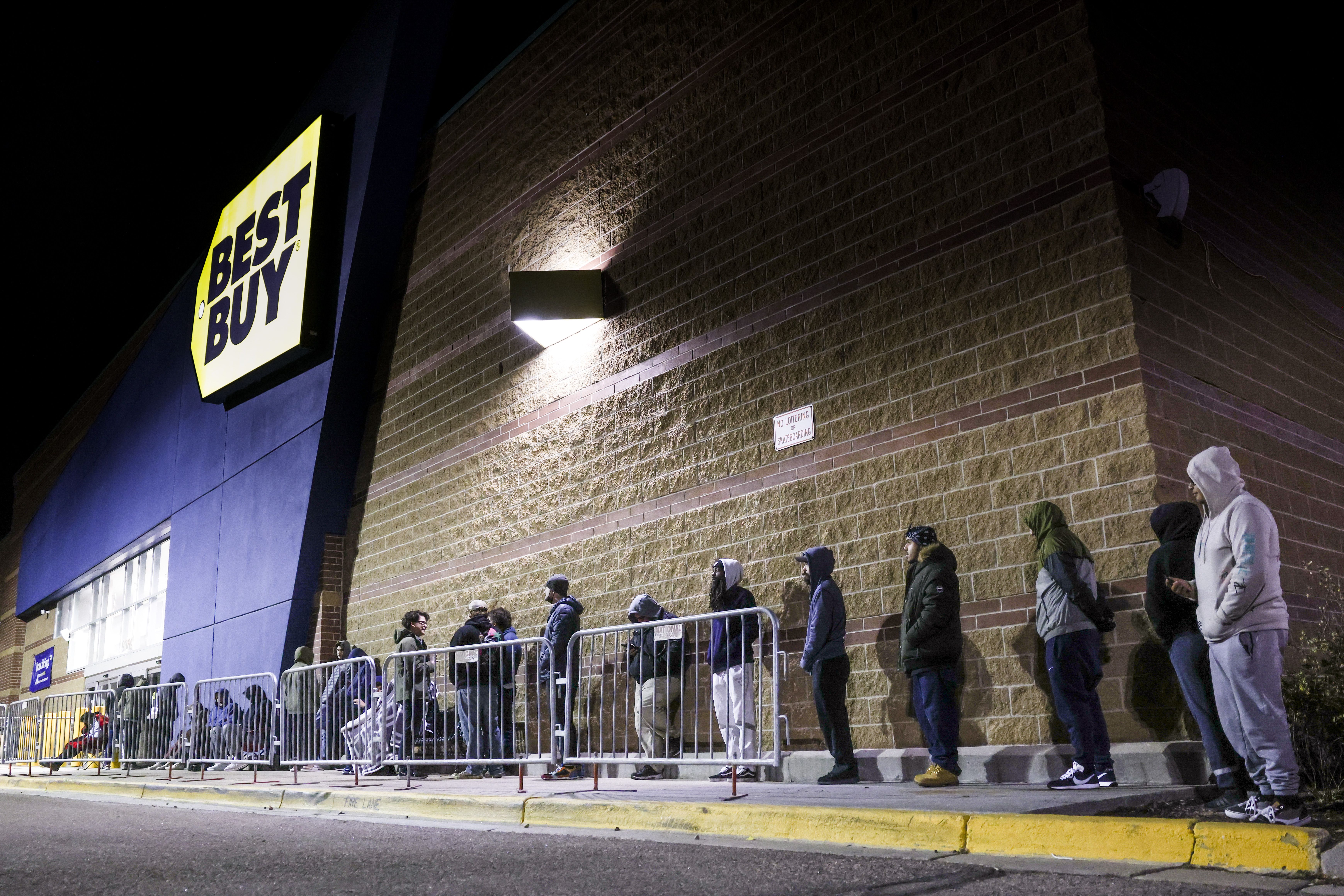 shoppers wait outside a best buy in the dark