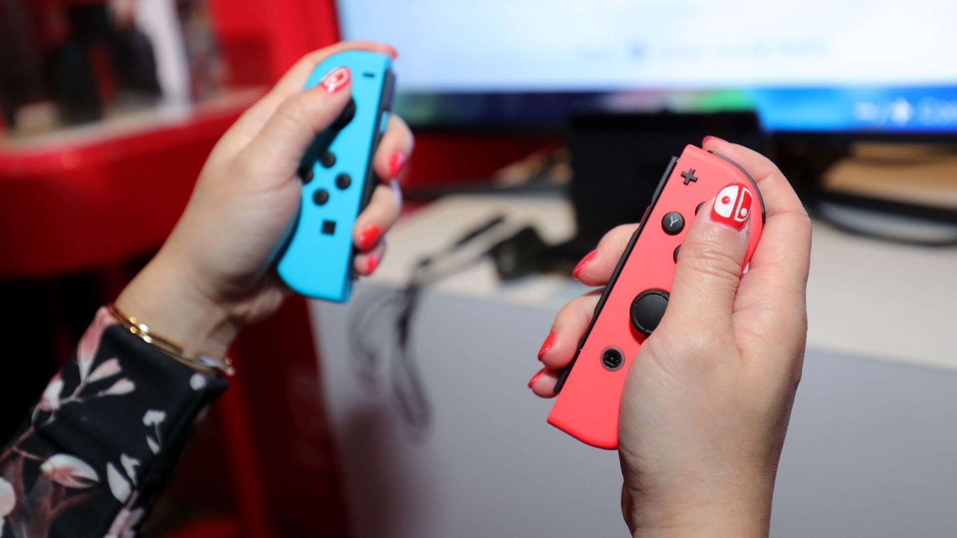 A pair of hands hold two Switch gaming consoles
