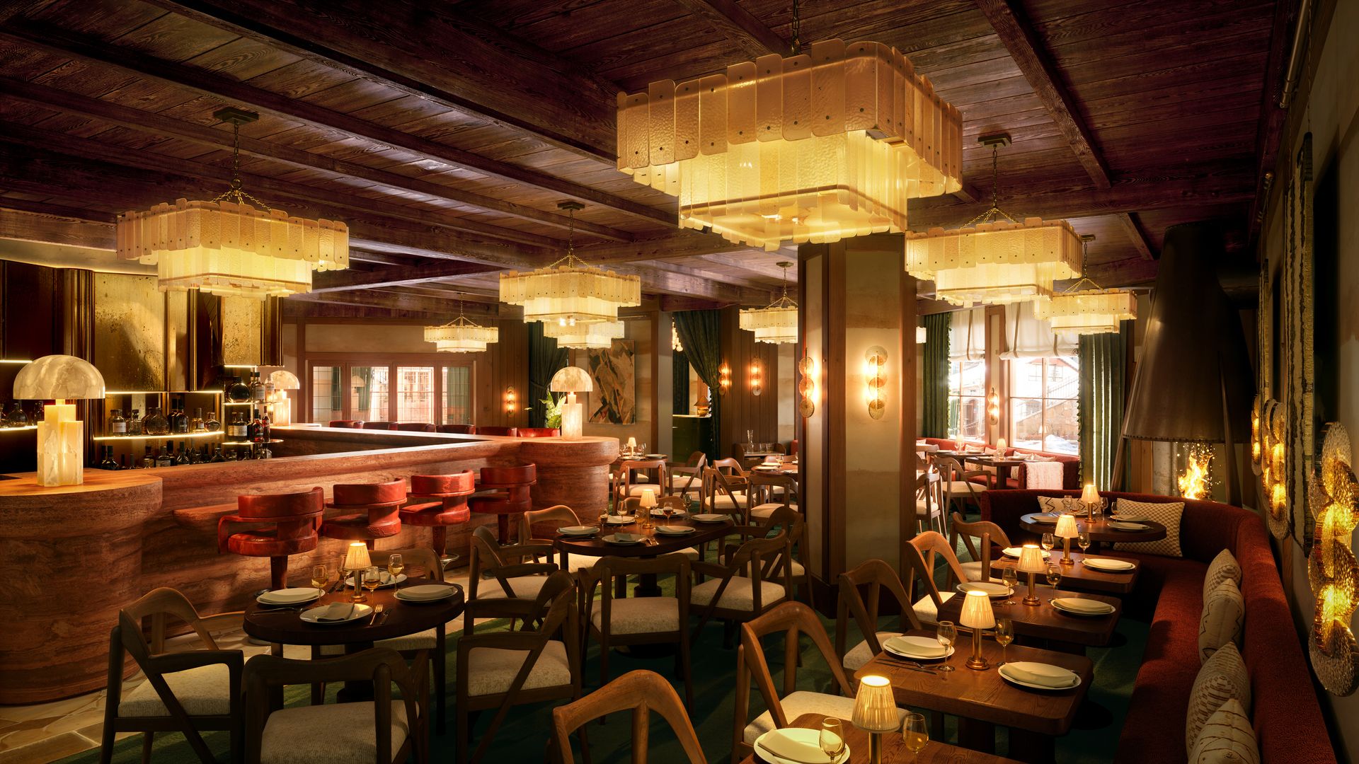 Interior of a cozy restaurant with wooden ceiling, amber chandeliers, round tables set with plates and glasses, red upholstered chairs and bar stools, green curtains, and a lit fireplace.