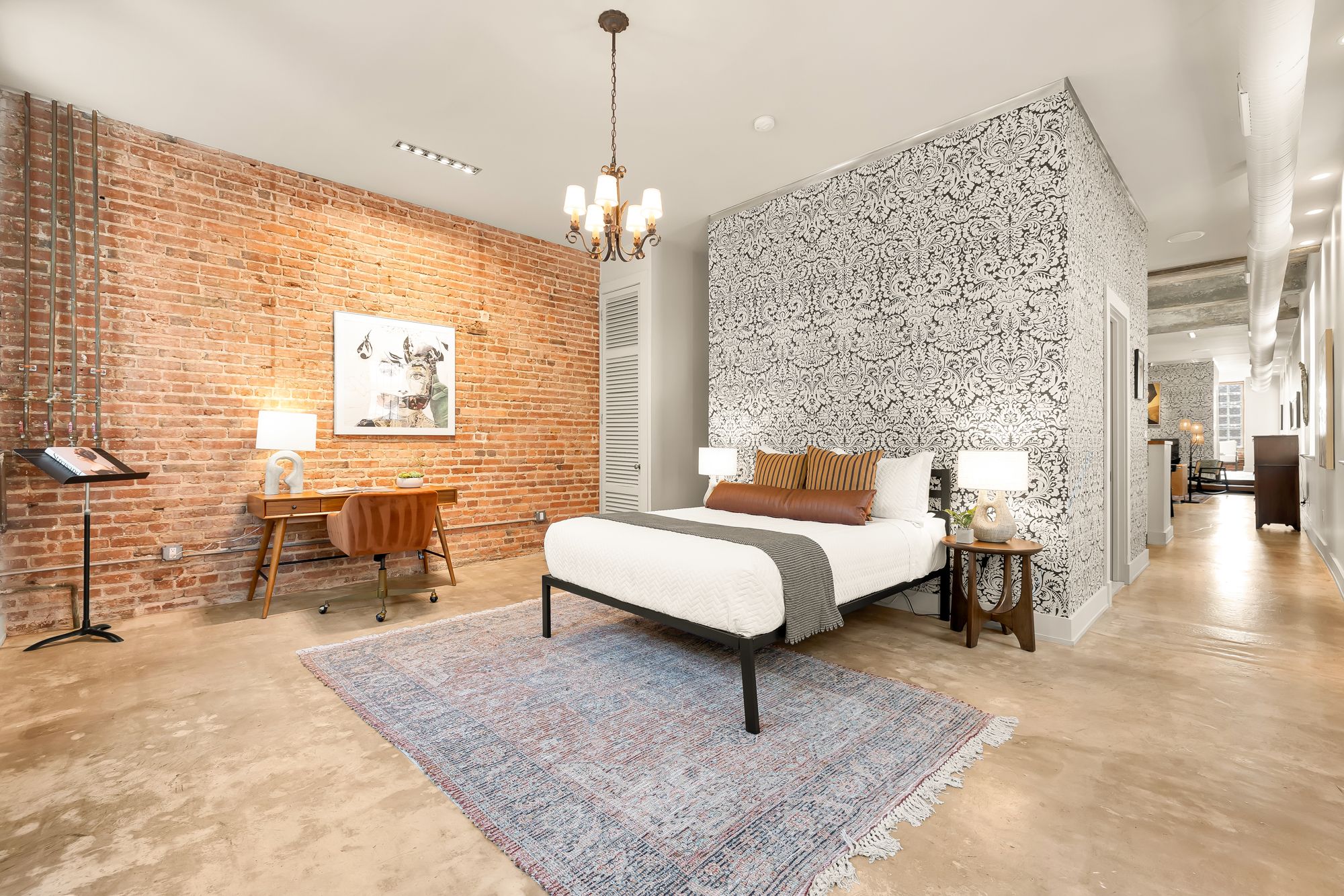 A bedroom with one exposed brick wall and another patterned statement wall. 