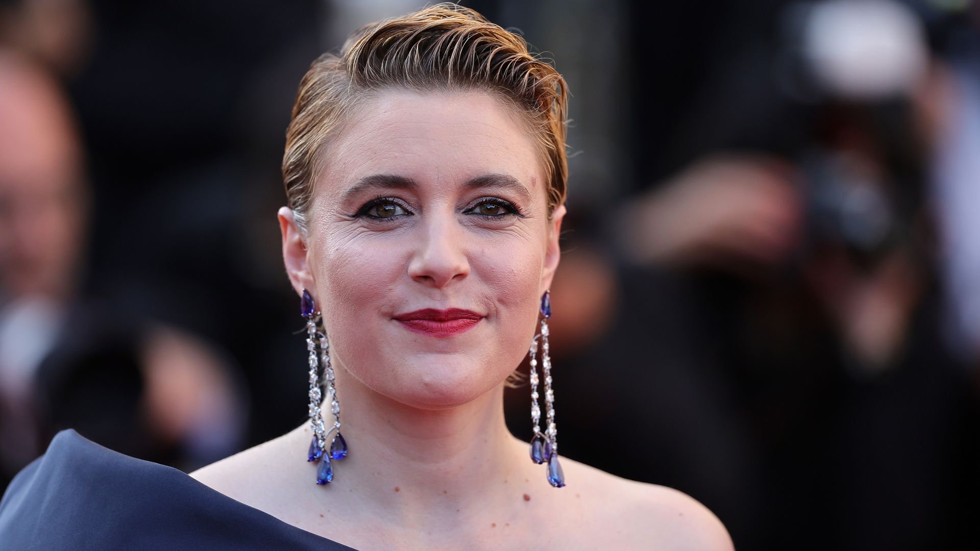 A person in a ball gown and long diamond earrings 