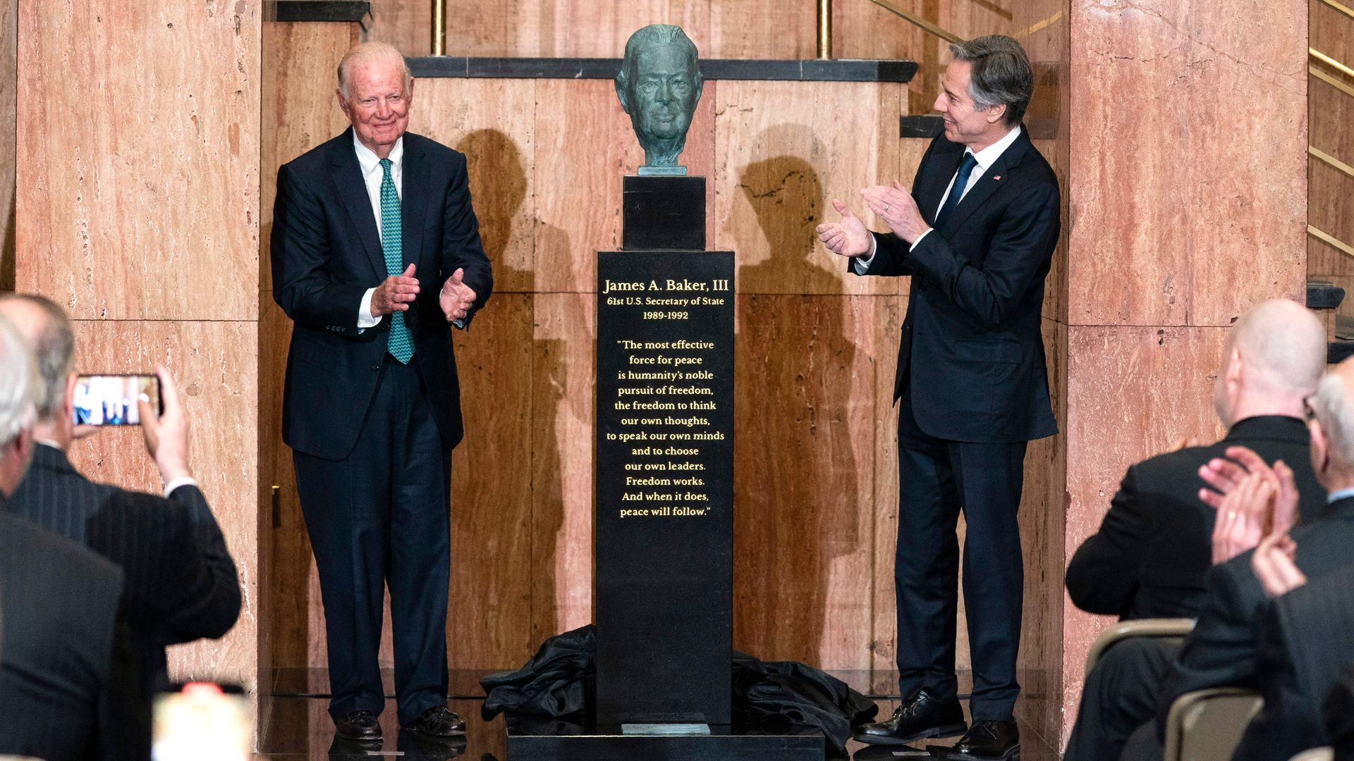 Secretary of State Antony Blinken is seen applauding with former Secretary James A. Baker III after unveiling a bust of Baker.