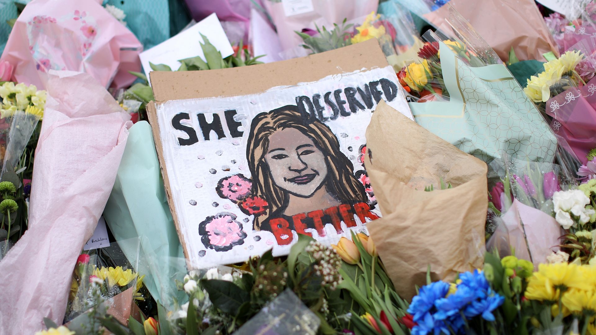 Picture of a floral tribute for Sarah Everard, in the center of the picture there's a drawing of Everard with the words "She deserved better."