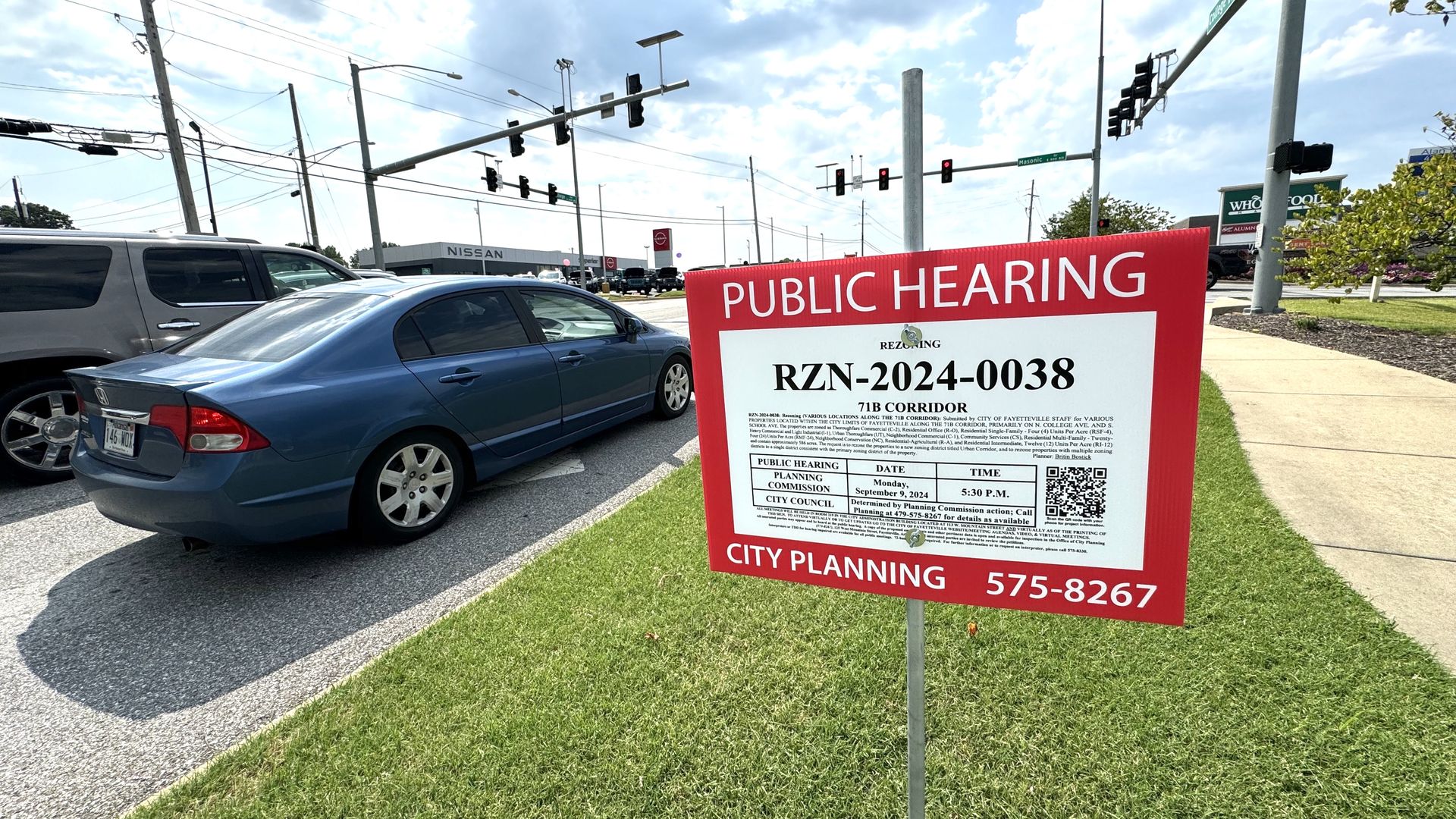 A photo of a sign on posted on the side of a road reading, in part, "public hearing."
