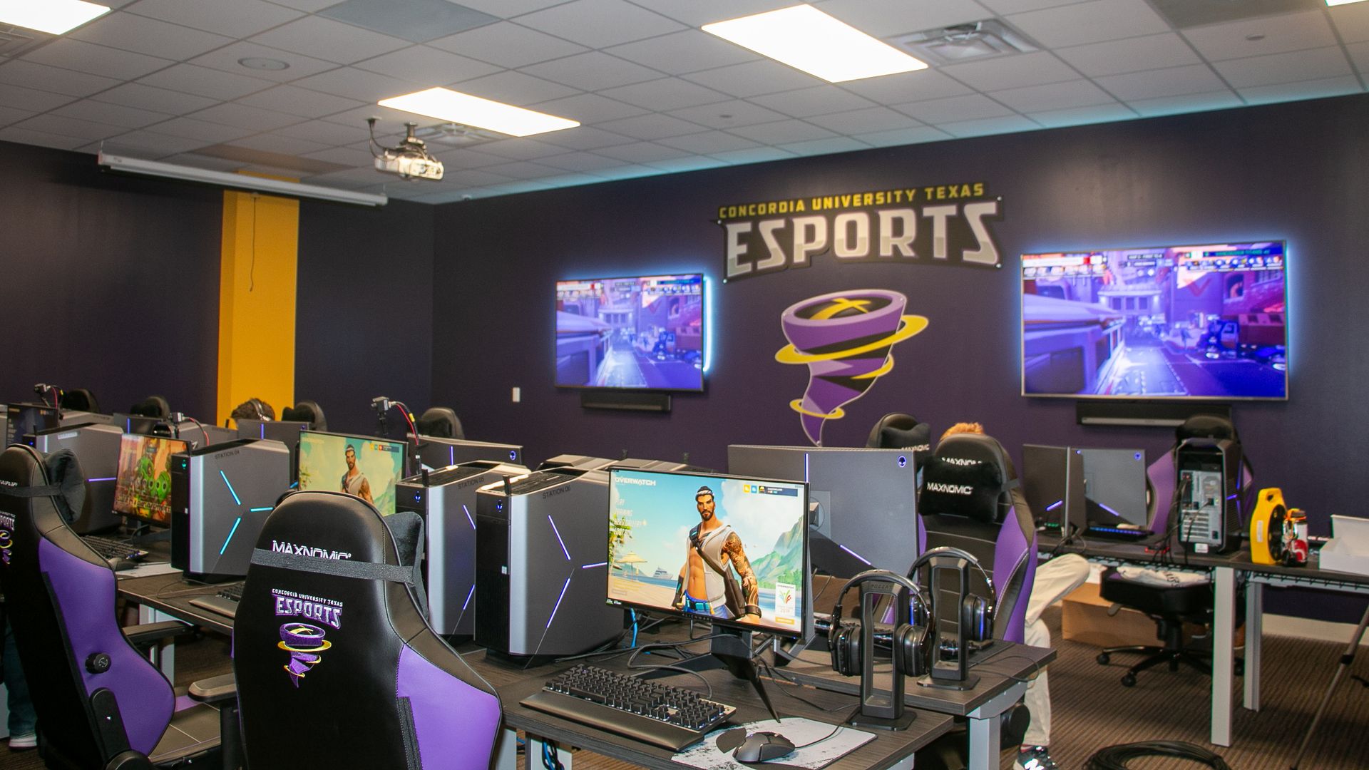 A photo of a eSports gaming room with desktop computers and monitors in the background.